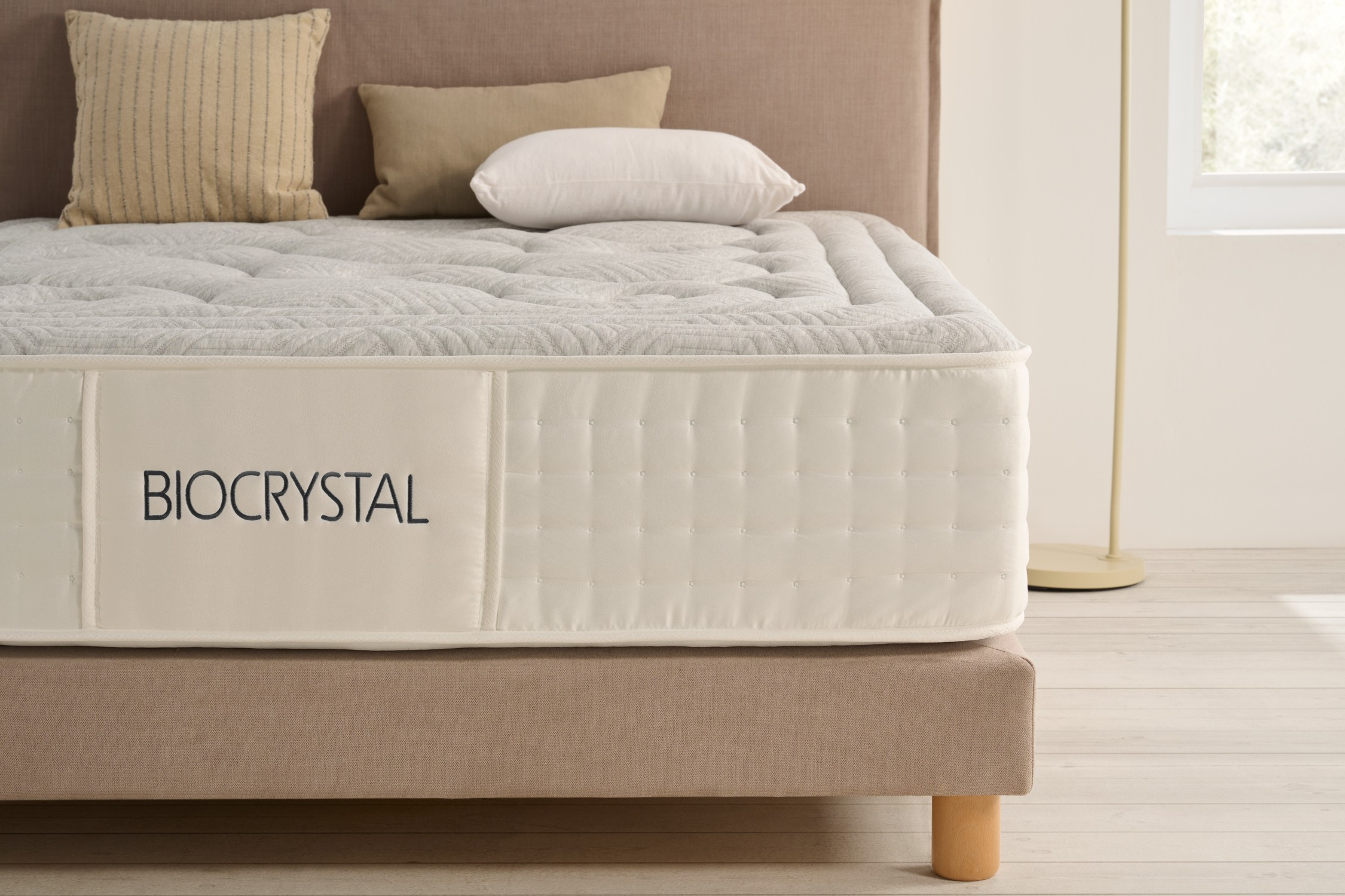 Un colchón blanco con el texto BIOCRYSTAL sobre una base de cama marrón.