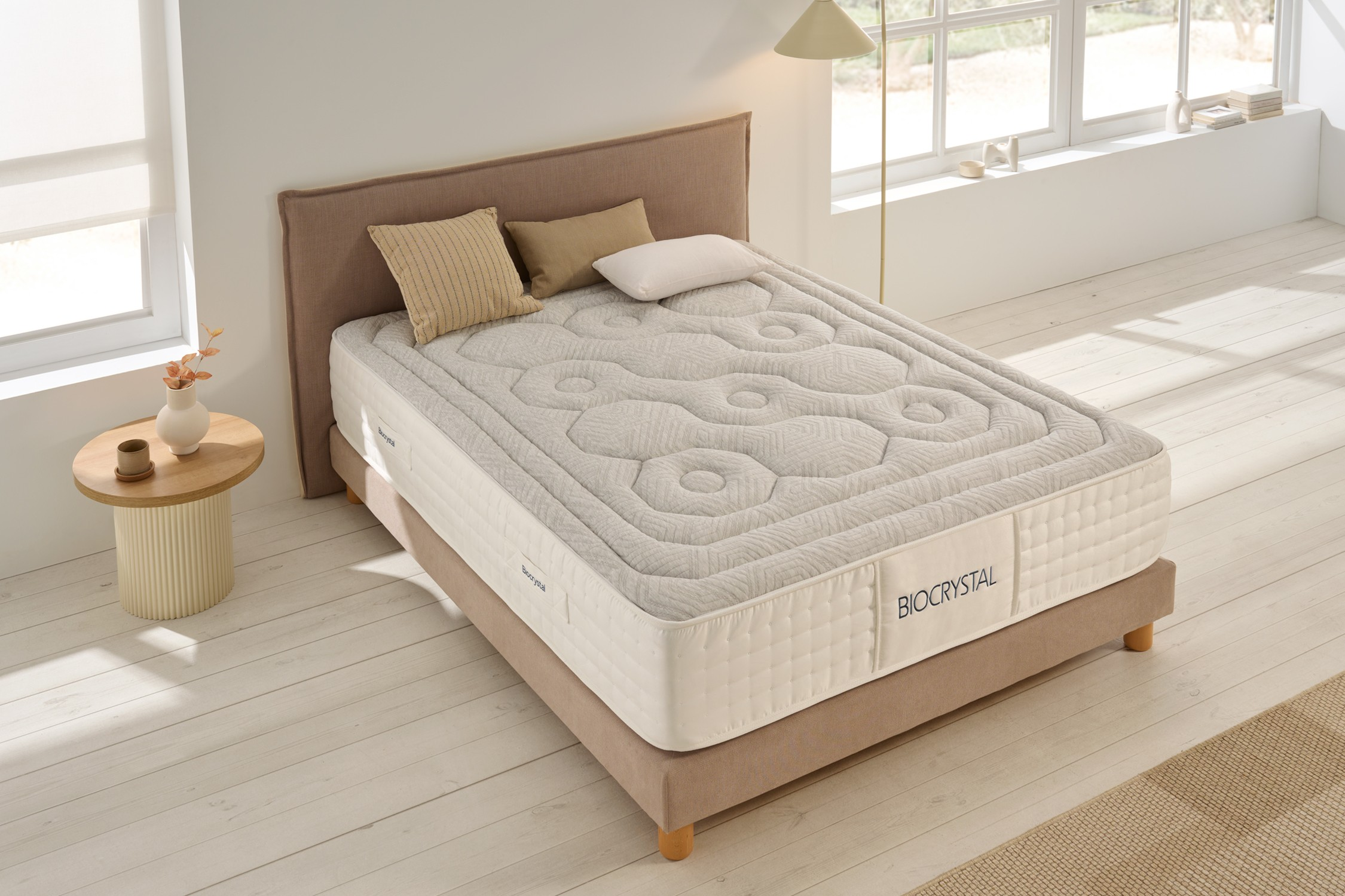 Una cama con colchón acolchado y almohadas descansa sobre tarimas de madera.