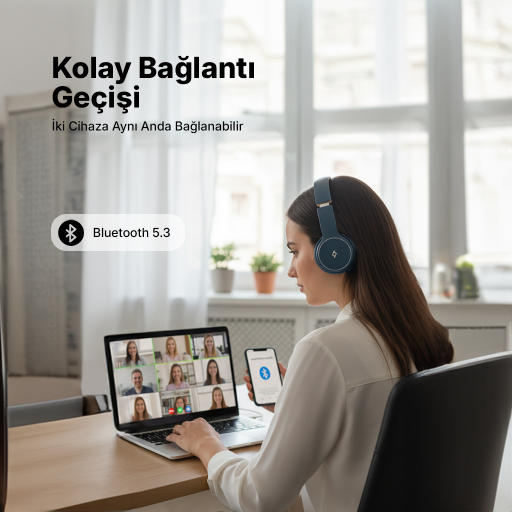 Kulaklıklı kadın masasında, dizüstü bilgisayara ve telefona bakıyor.