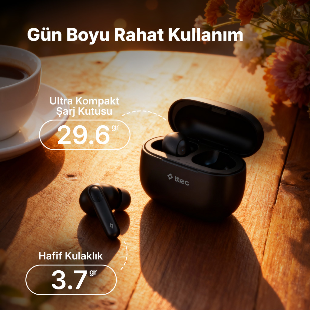 Tahta masada siyah kablosuz kulaklık, kahve fincanı ve çiçek yanında.