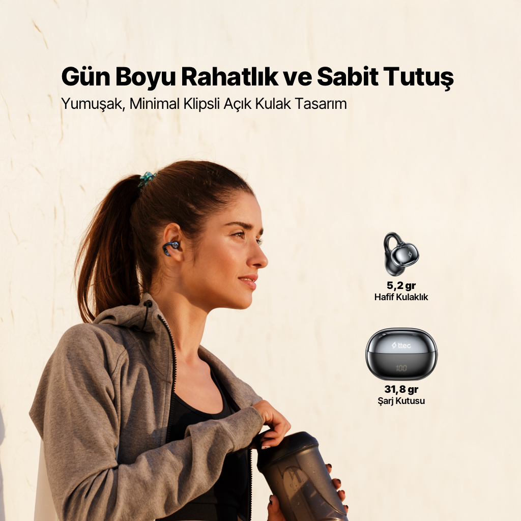Kadın kulaklık takmış su şişesi tutuyor. Yanında kulaklık ve şarj kutusu var.
