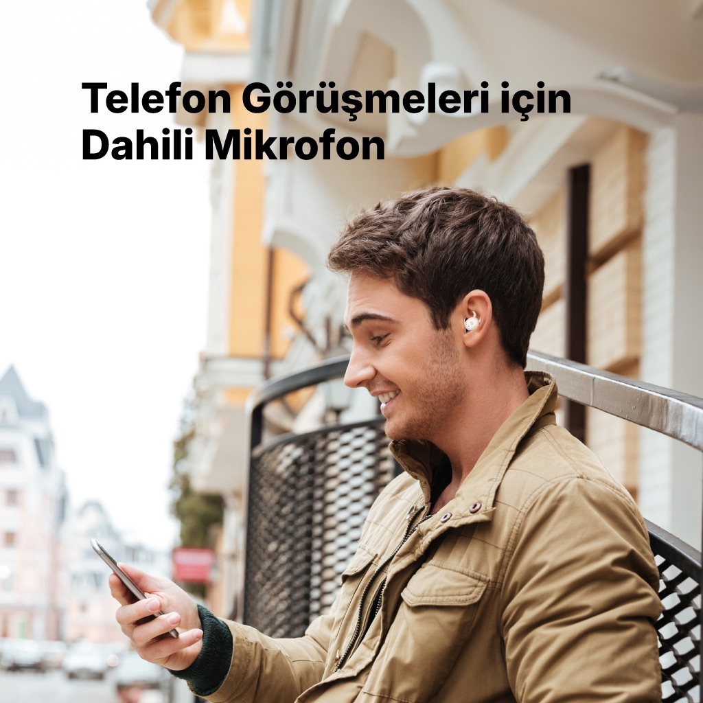 Kulaklıklı ve telefonlu bir adam dışarıdaki merdivenlerde oturuyor.