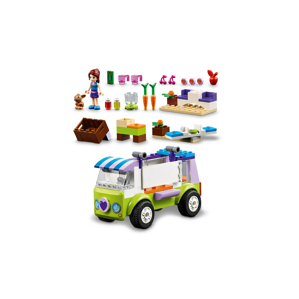 Un furgone Lego verde con strisce viola e blu, accanto a una figura e accessori.