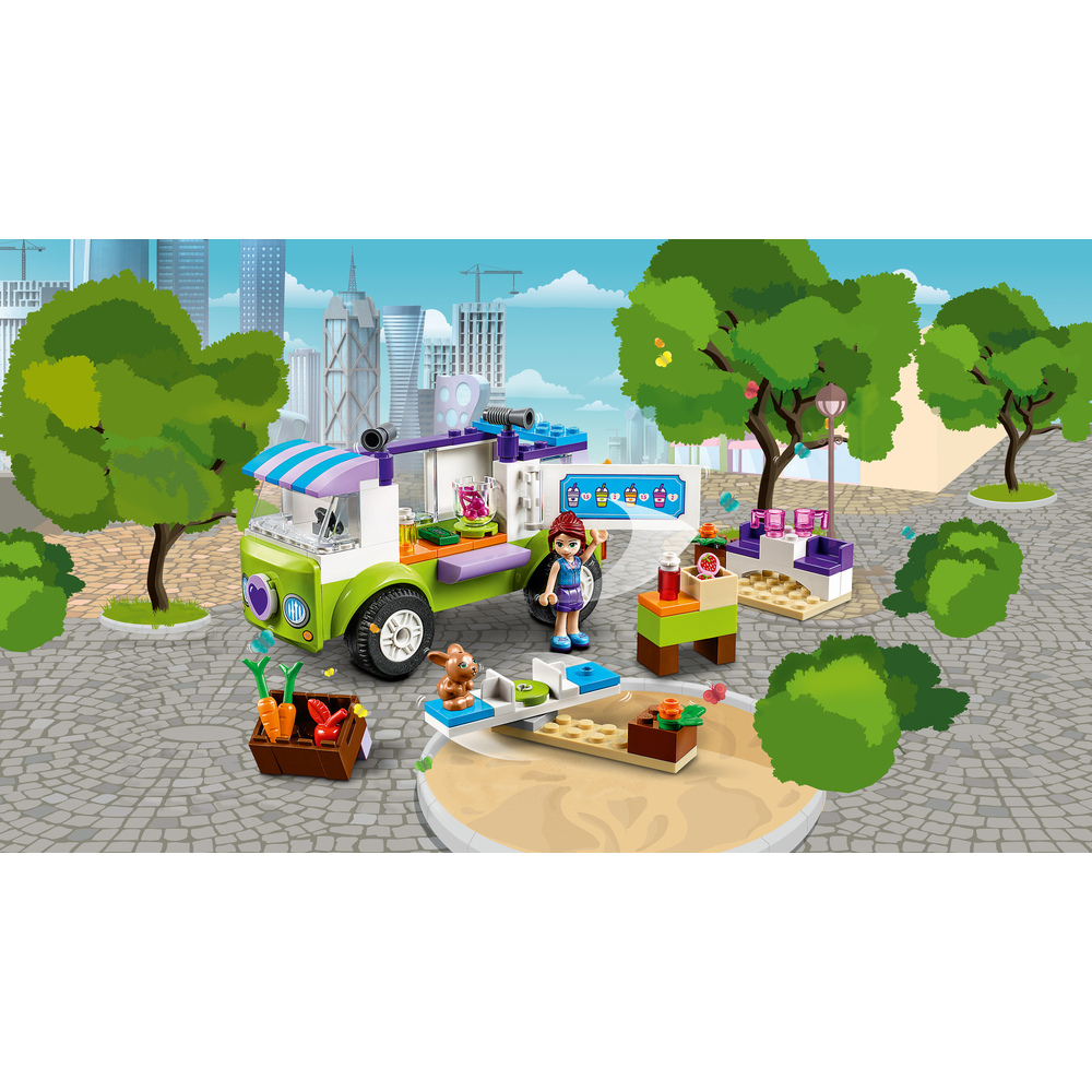 Carretto di succhi Lego verde e viola con ragazza, coniglietto e chiosco in un parco.