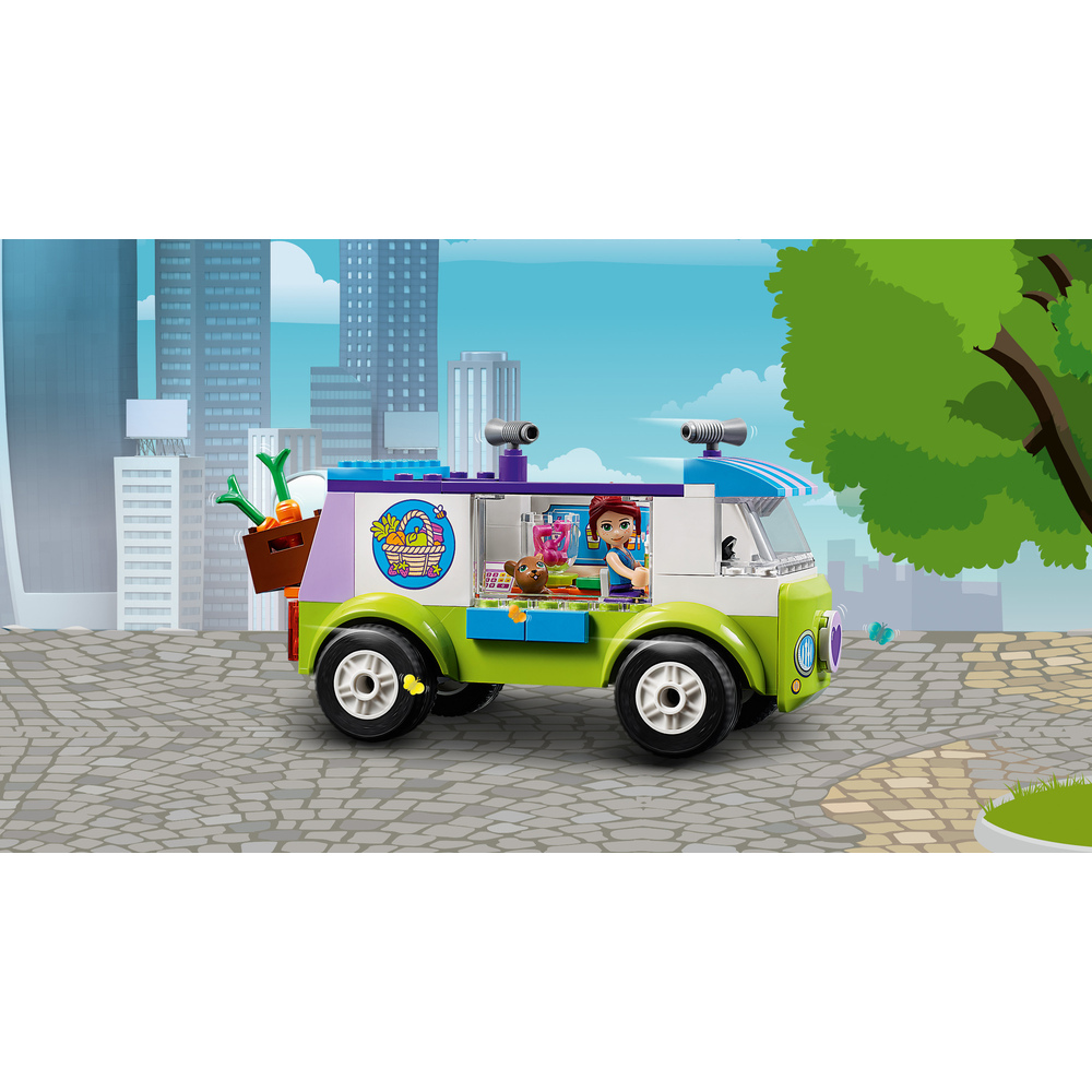 Un furgone Lego verde e bianco con una ragazza e un orso all'interno, parcheggiato in strada.