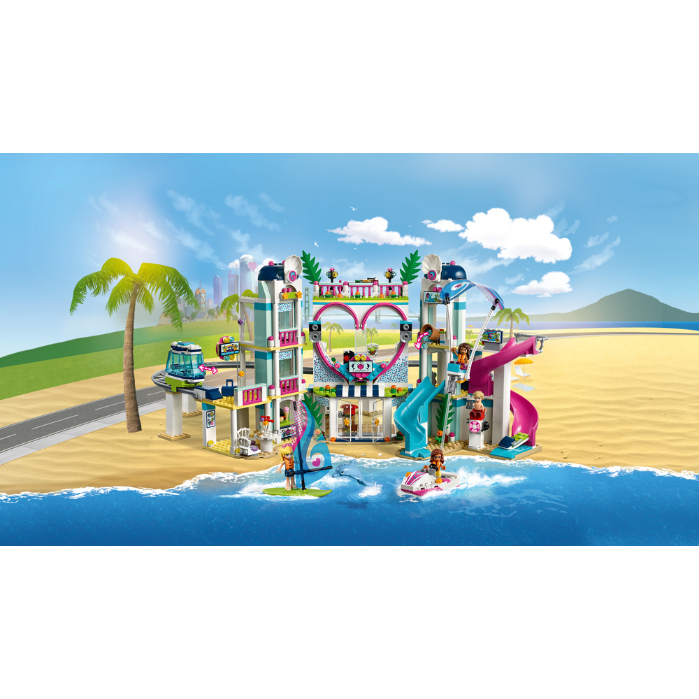 Un resort Lego su una spiaggia con scivoli, barche e palme.
