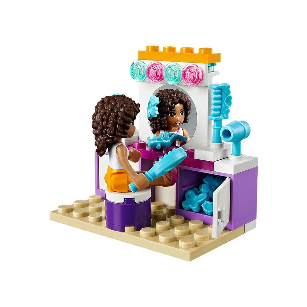Bambina Lego si pettina allo specchio con spazzola e asciugacapelli.