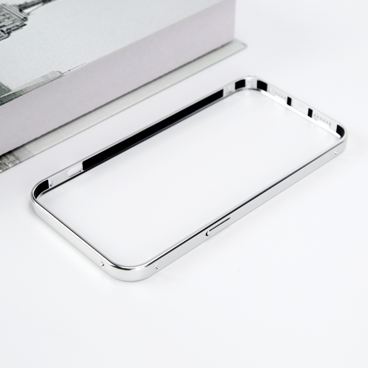 Una cornice argentata per telefono con accenti neri poggia su un libro.