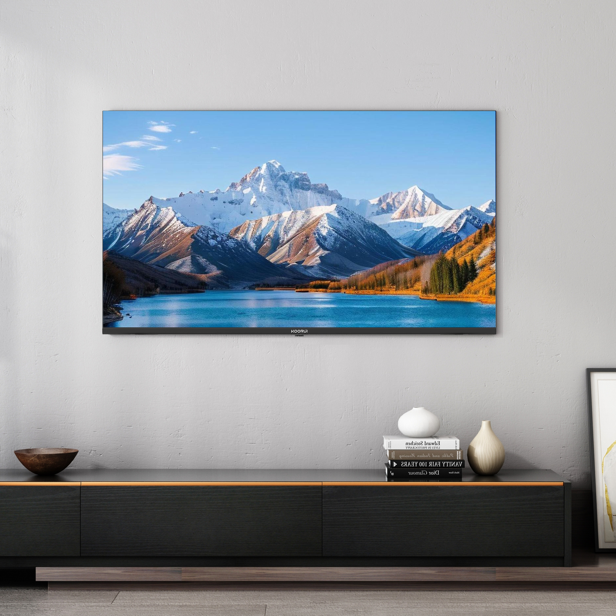 Ein Flachbildfernseher zeigt eine Berglandschaft mit einem See und schneebedeckten Gipfeln.