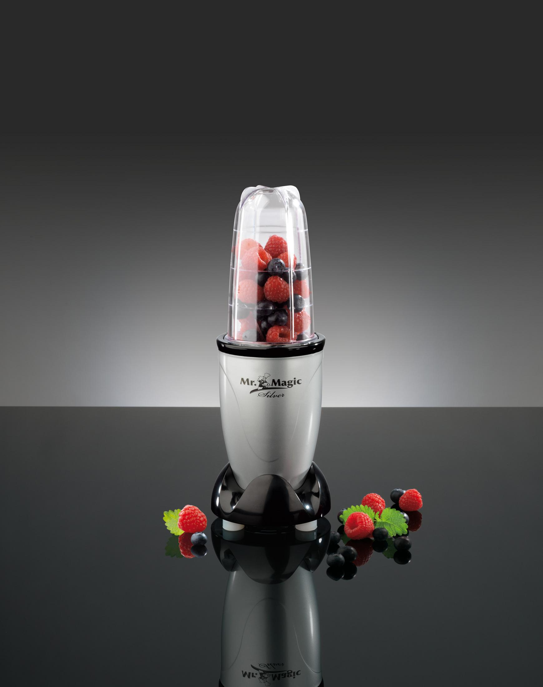 Ein silberner Mixer mit Beeren gefüllt, auf schwarzem Spiegelgrund.