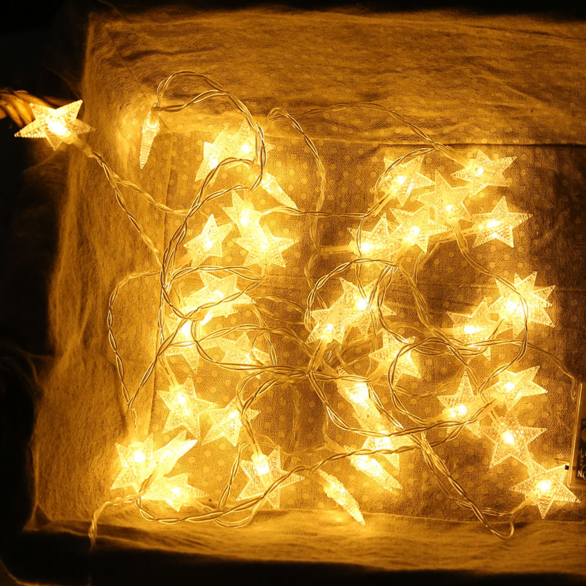 Eine Lichterkette mit Sternen auf einem Stoffhintergrund.