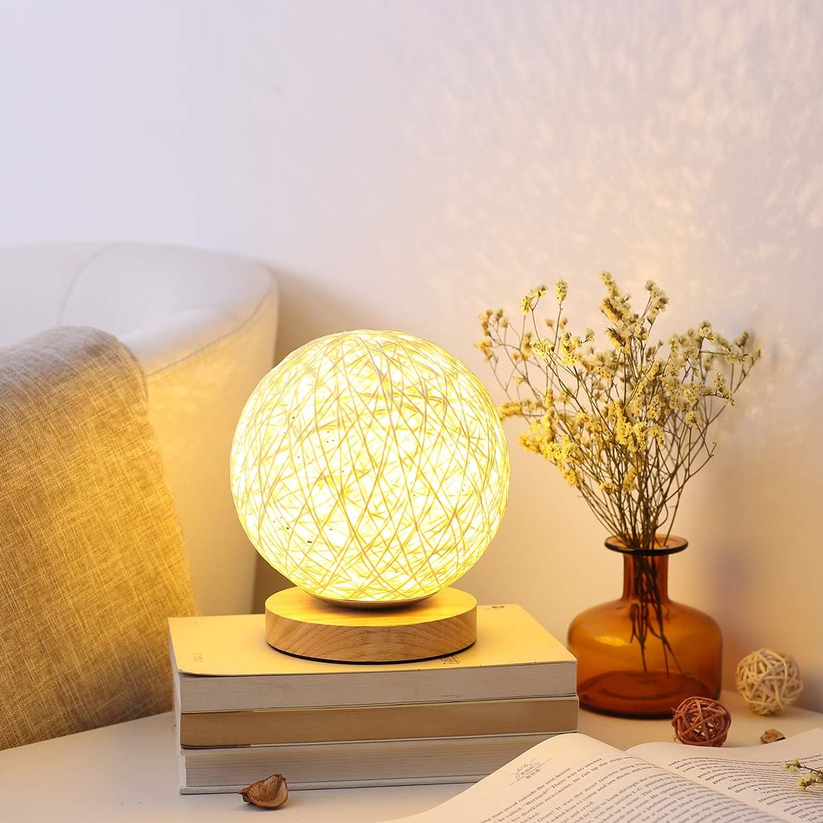 Eine Nachttischlampe mit einem runden Korbmuster-Schirm steht auf Büchern.