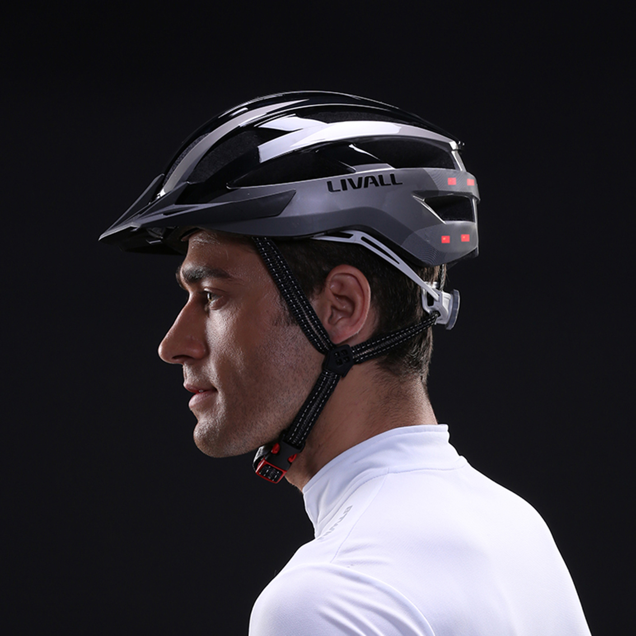 Ein Mann trägt einen schwarzen und grauen Fahrradhelm mit roten Rückleuchten.