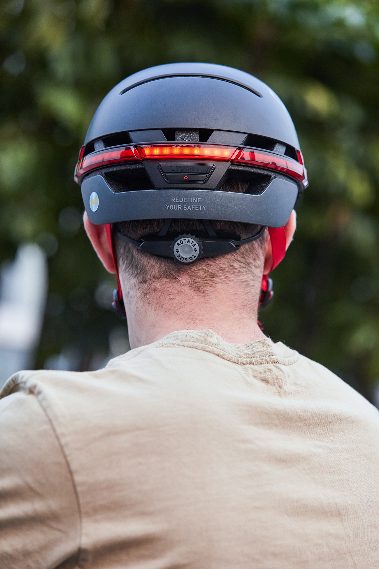 Rückansicht eines Mannes mit schwarzem Helm, der rote Rücklichter hat.