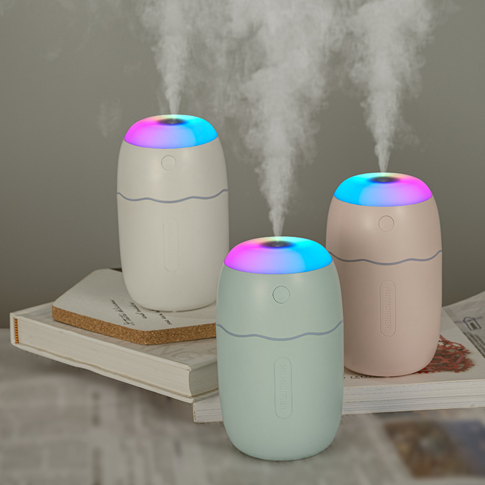 Drei Luftbefeuchter mit farbiger LED-Beleuchtung auf Büchern.