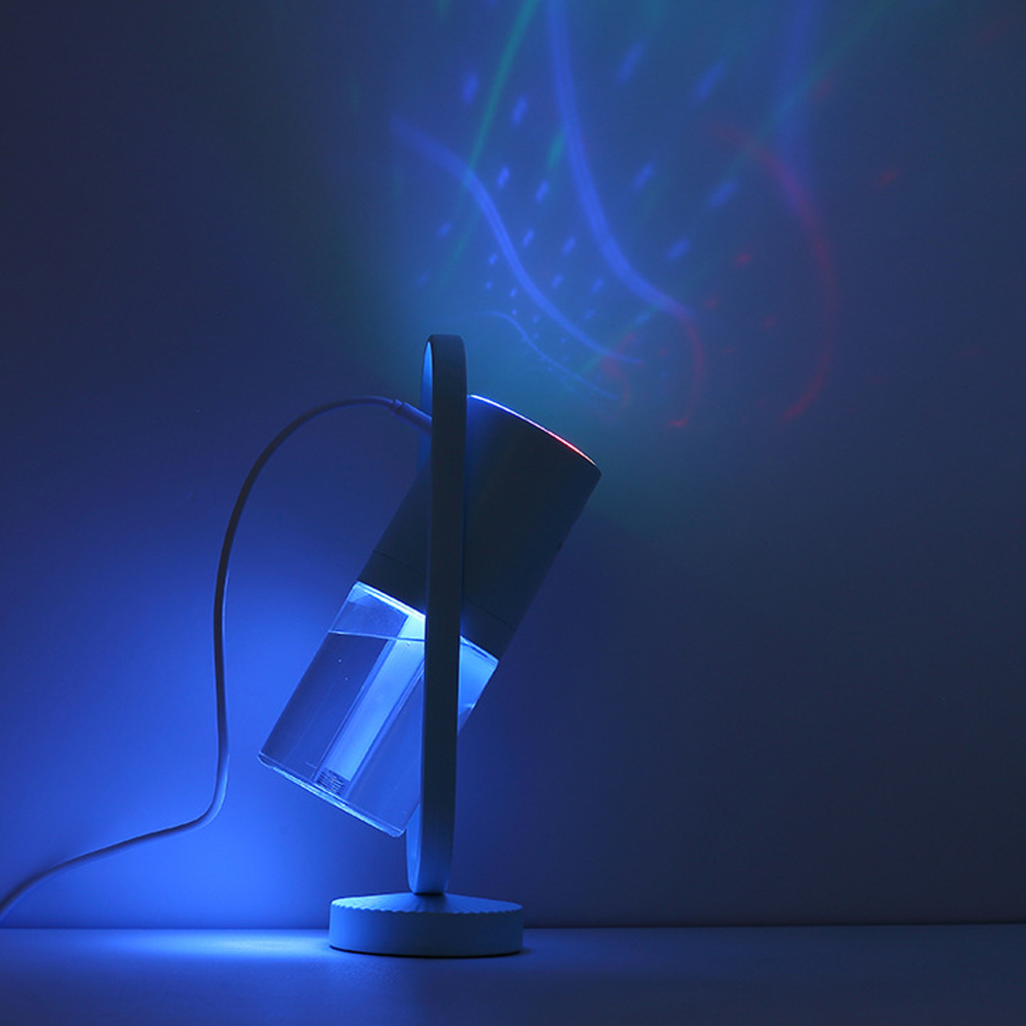 Ein blau beleuchteter Projektor wirft farbige Lichter an eine Wand.