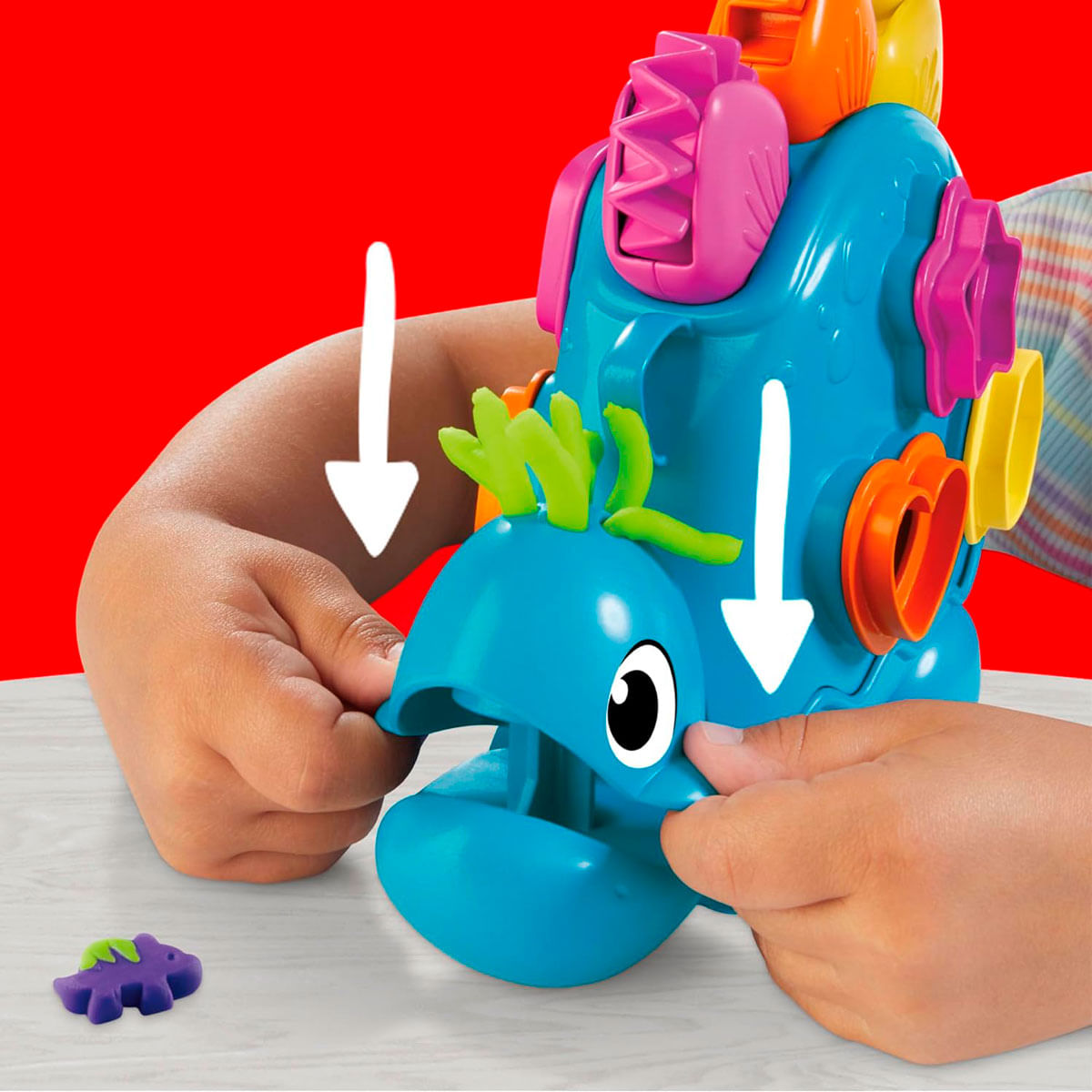 Manos de niño dan forma a dinosaurio azul con cortadores y plastilina.