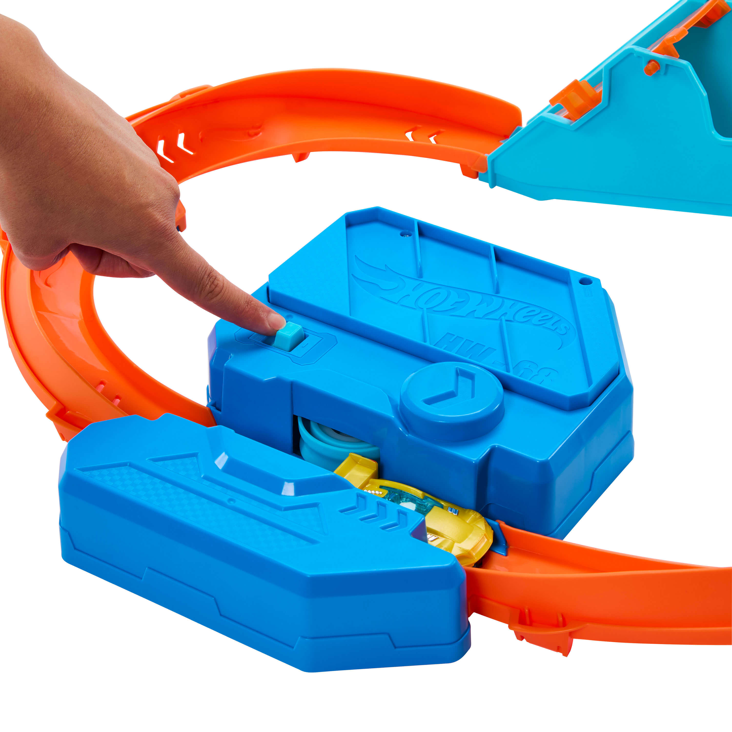 Un dedo presiona un botón azul en un set de pista azul de Hot Wheels con curvas naranjas.