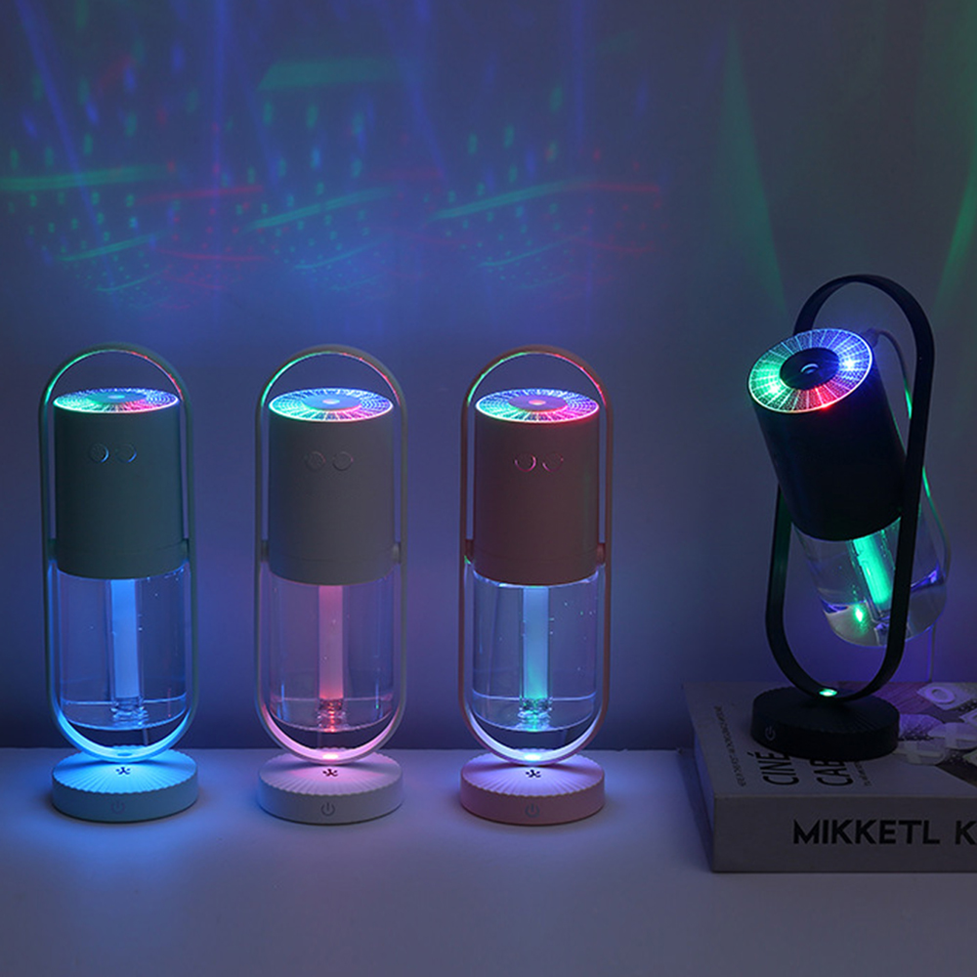 Vier bunte Luftbefeuchter mit LED-Lichtern und Lichtmustern an der Wand.