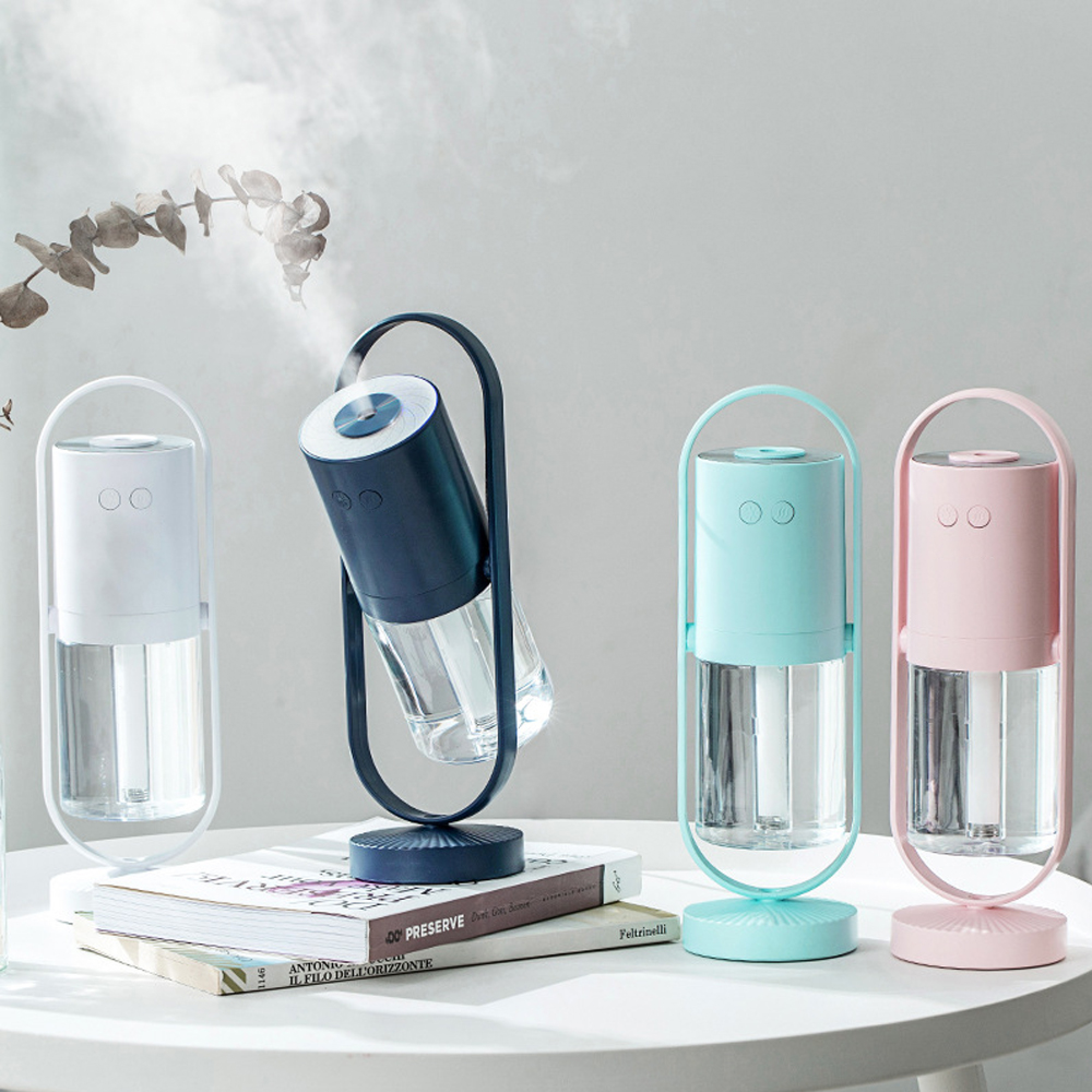 Vier Diffusoren in Pastellfarben: wei, blau, mintgrün und rosa, auf Büchern.