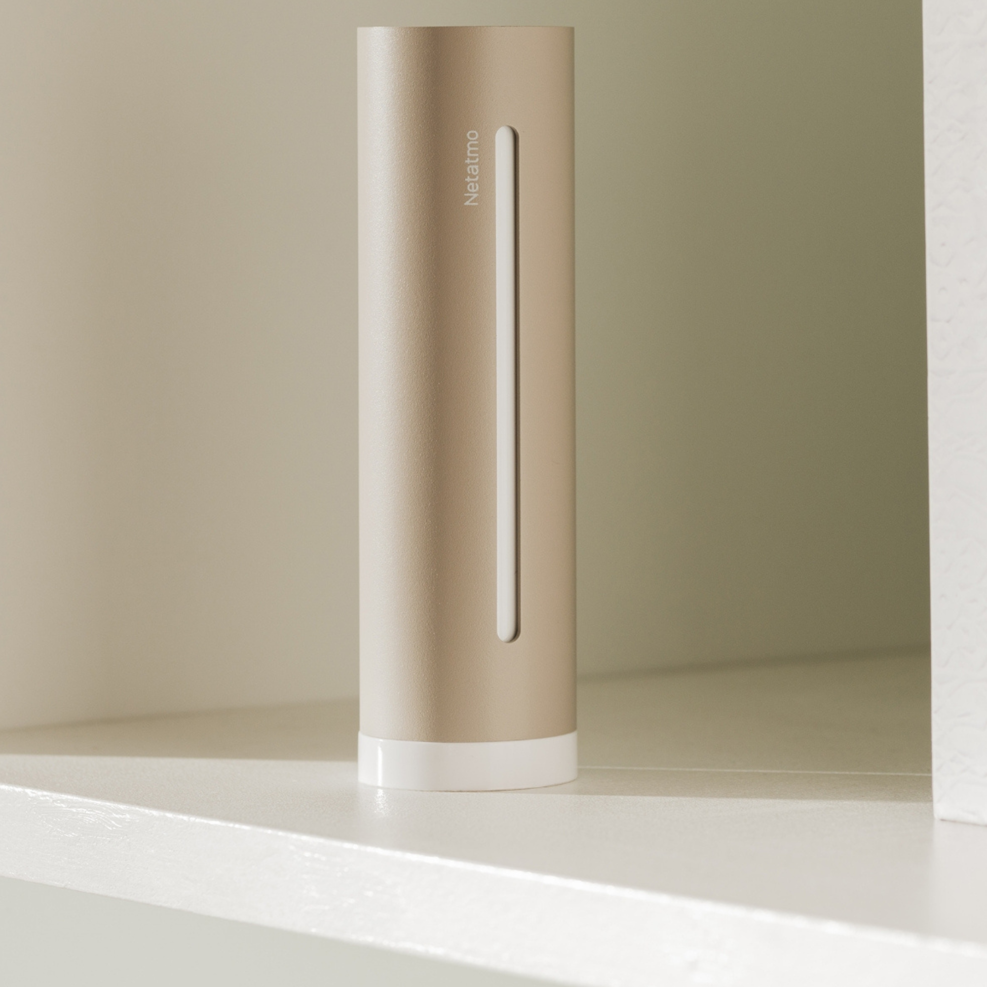 Een slanke, bronskleurige cilinder met een witte verticale streep staat op een lichtgekleurde plank.