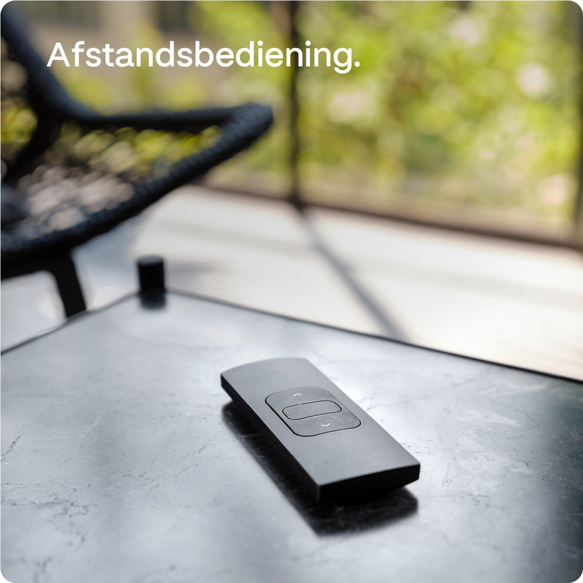Black remote control on a table with text 'Afstandbediening'.