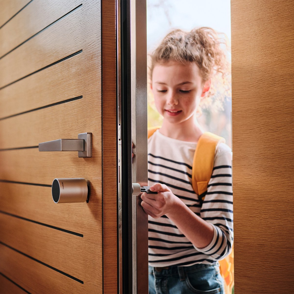 Girl with backpack unlocks door.