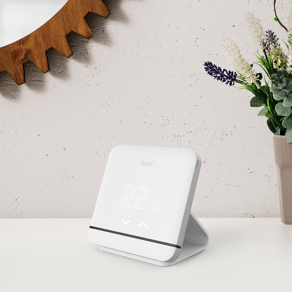 A white thermostat with a display showing 22.6°C. Flowers are next to it.