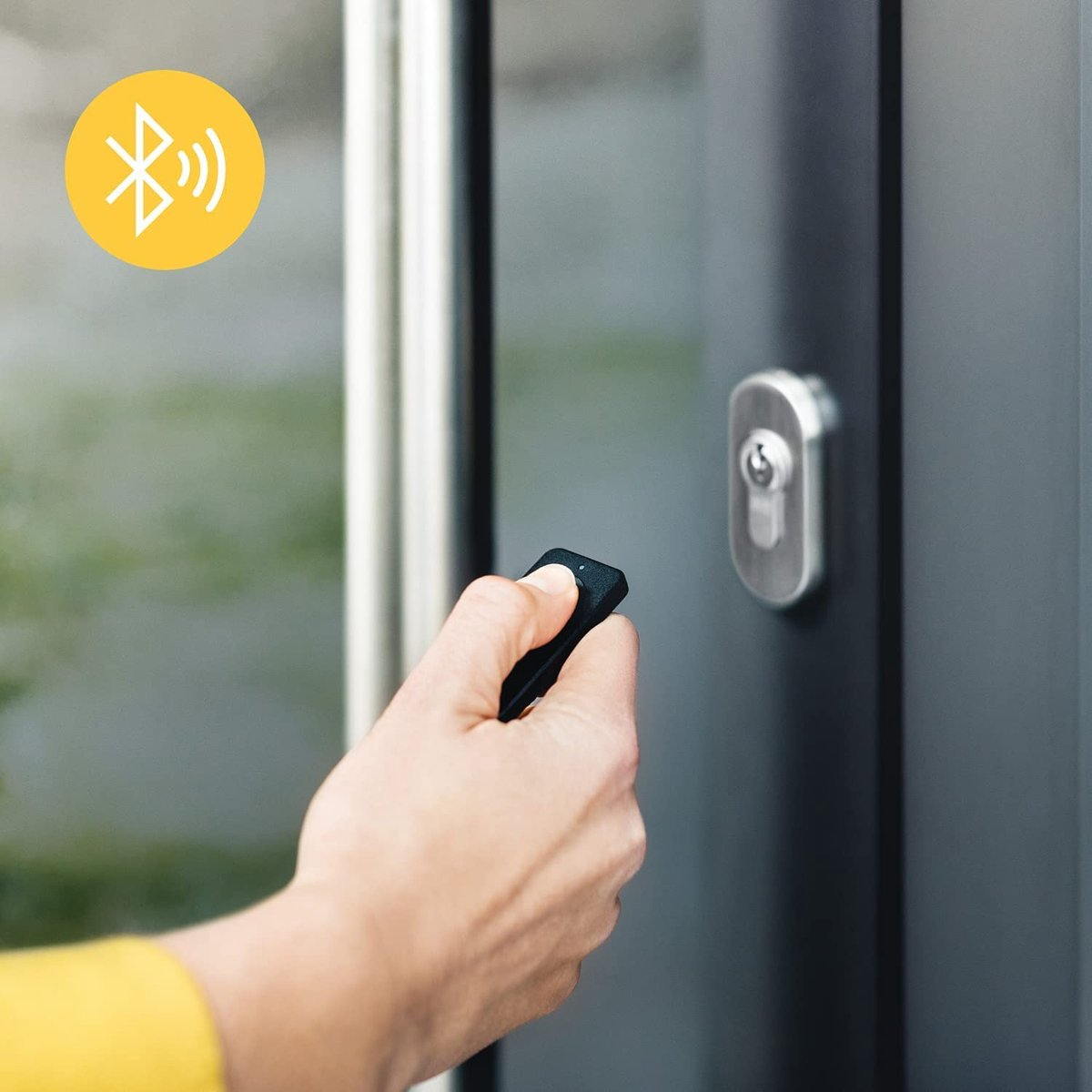 Hand holding remote to unlock door with Bluetooth symbol.