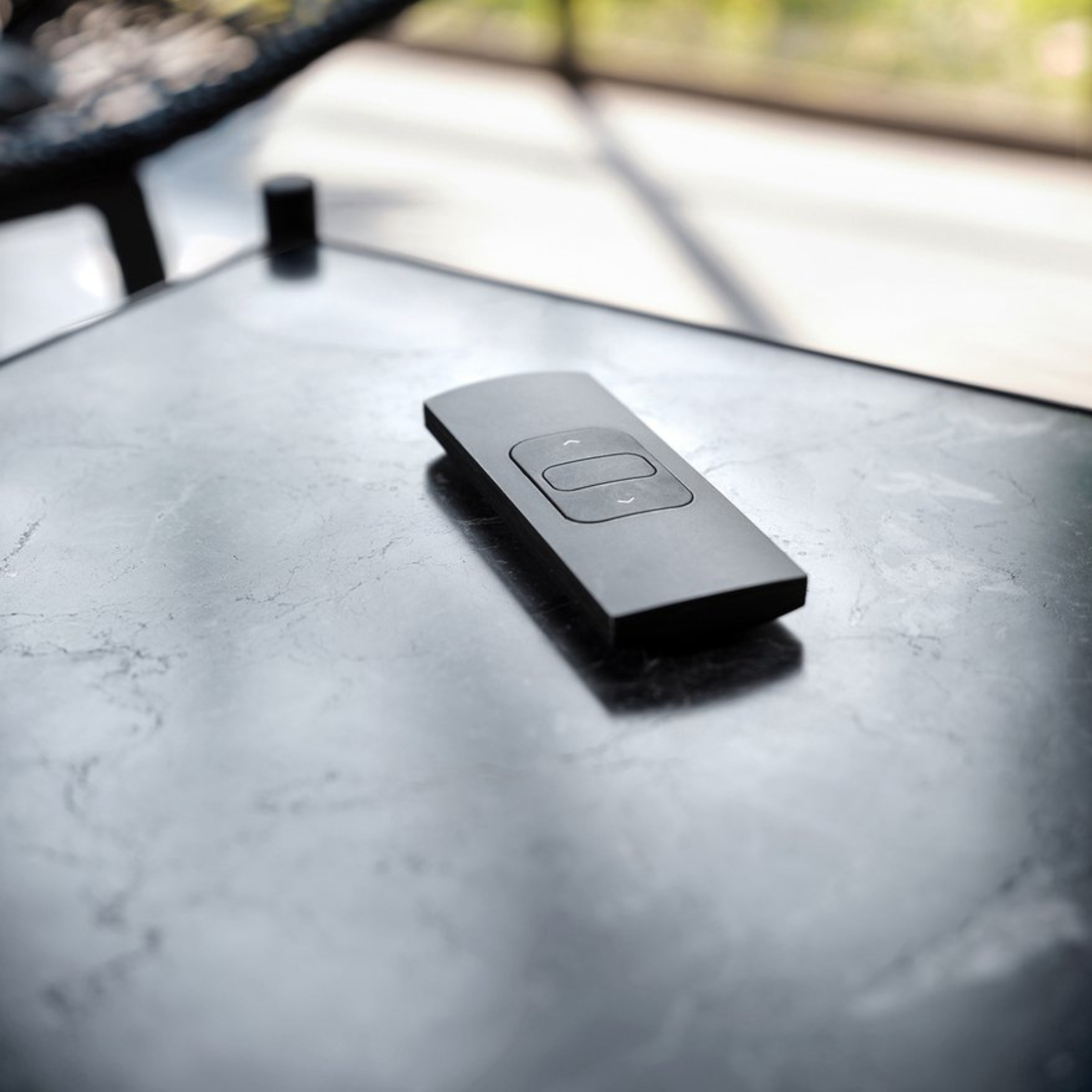 A black remote control rests on a marble table.