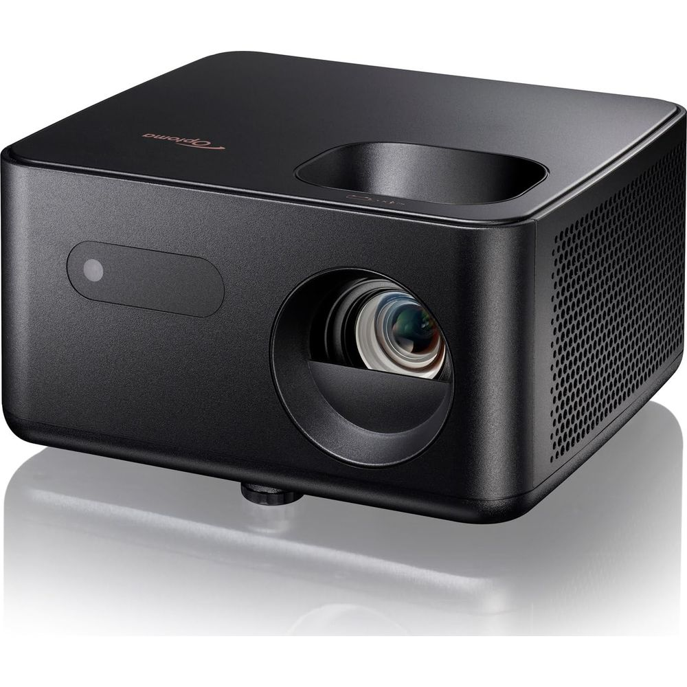 Un proyector Optoma negro está sobre una superficie reflectante. Tiene una lente en el frontal.