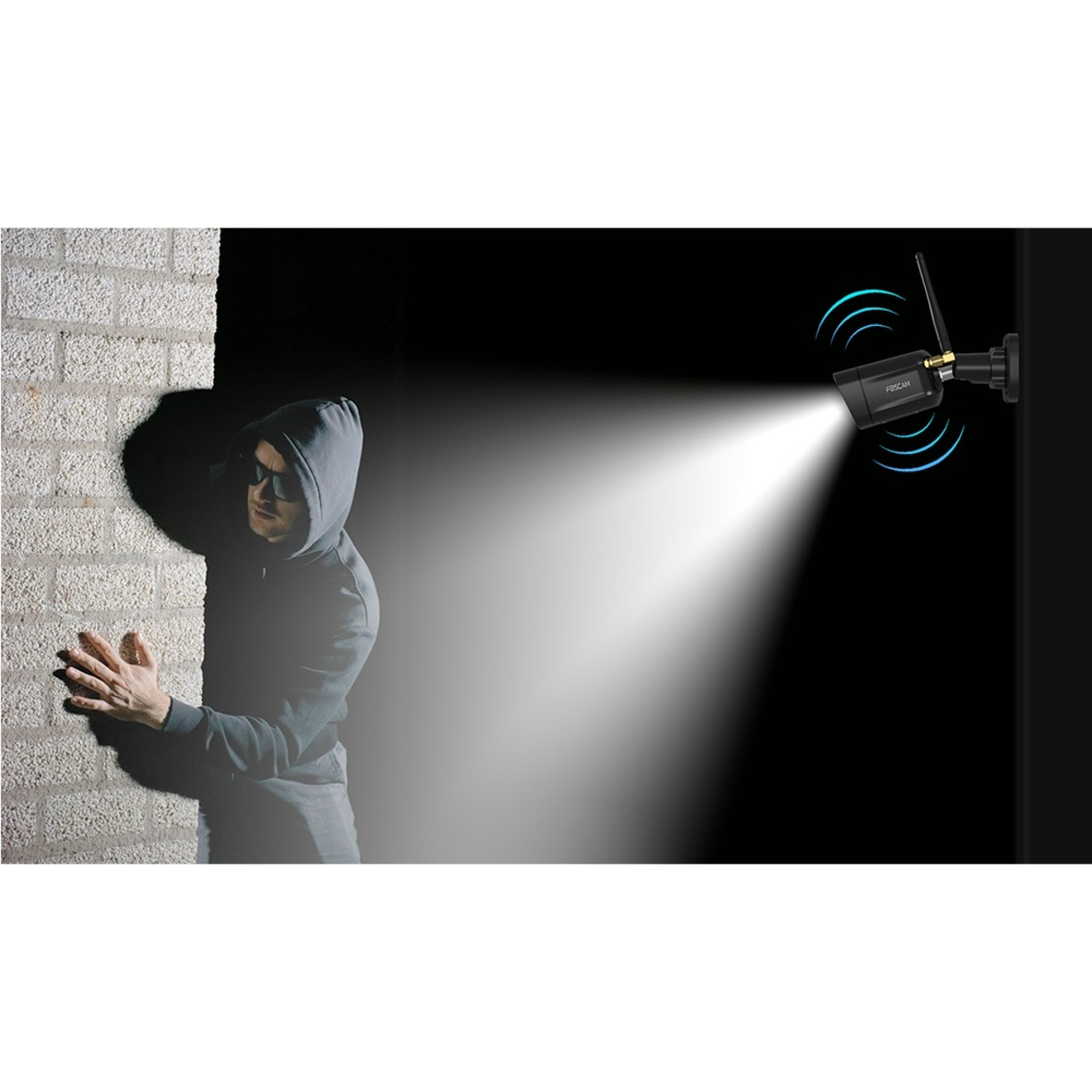 Un homme à capuche et lunettes de soleil se faufile le long d'un mur, éclairé par une caméra.