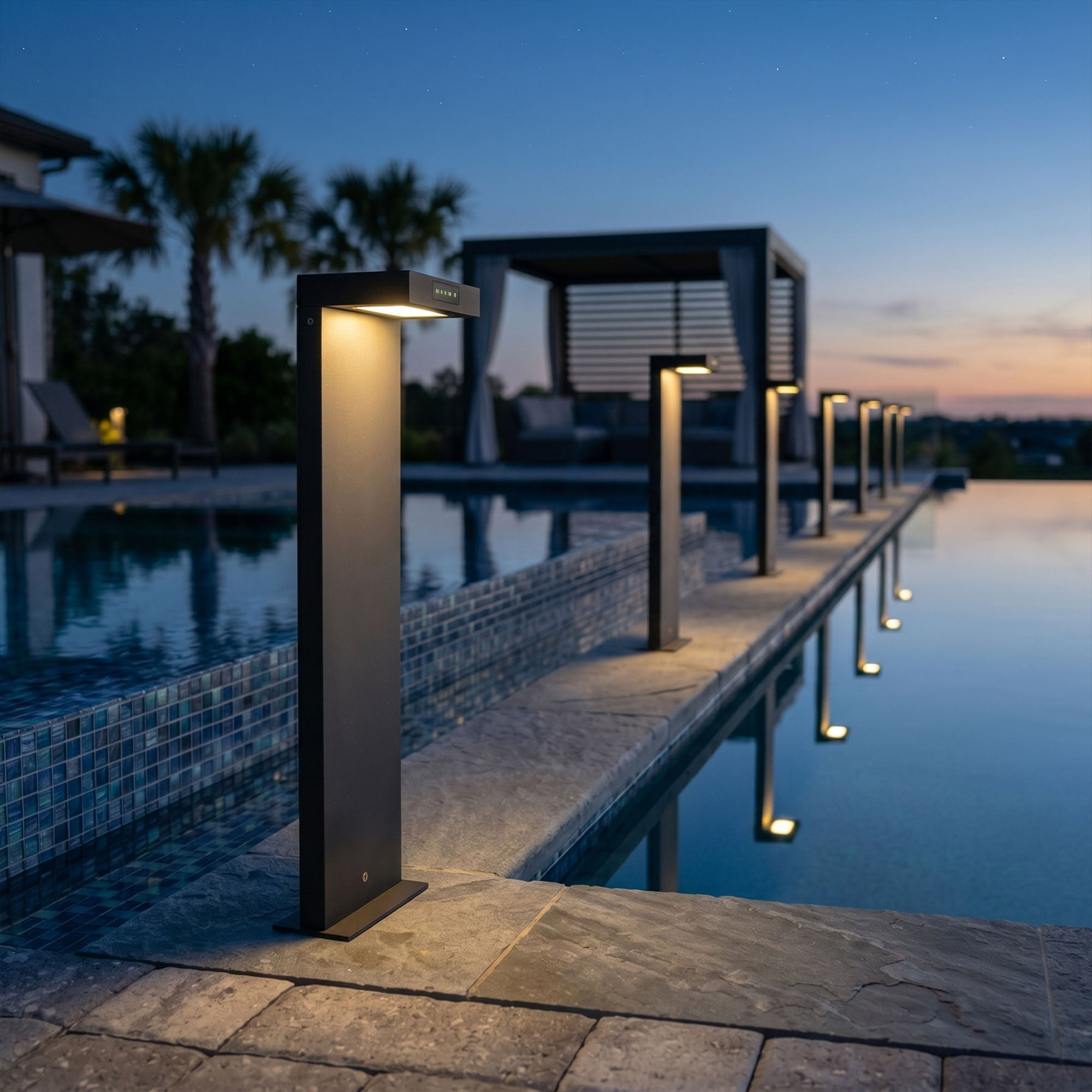 Moderne Außenleuchten säumen einen Pool bei Sonnenuntergang mit Palmen und Pavillon.