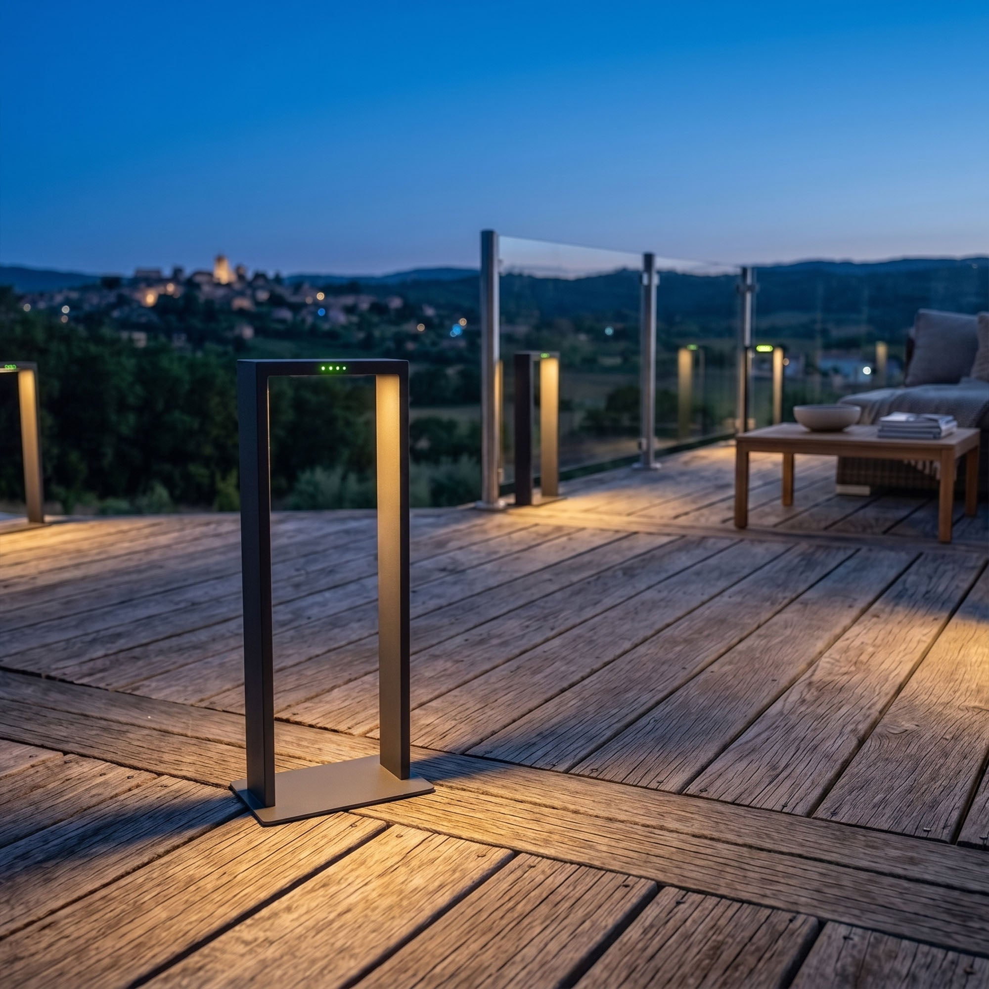 Moderne Lampen beleuchten eine Holzterrasse bei Dämmerung mit Stadtblick im Hintergrund.