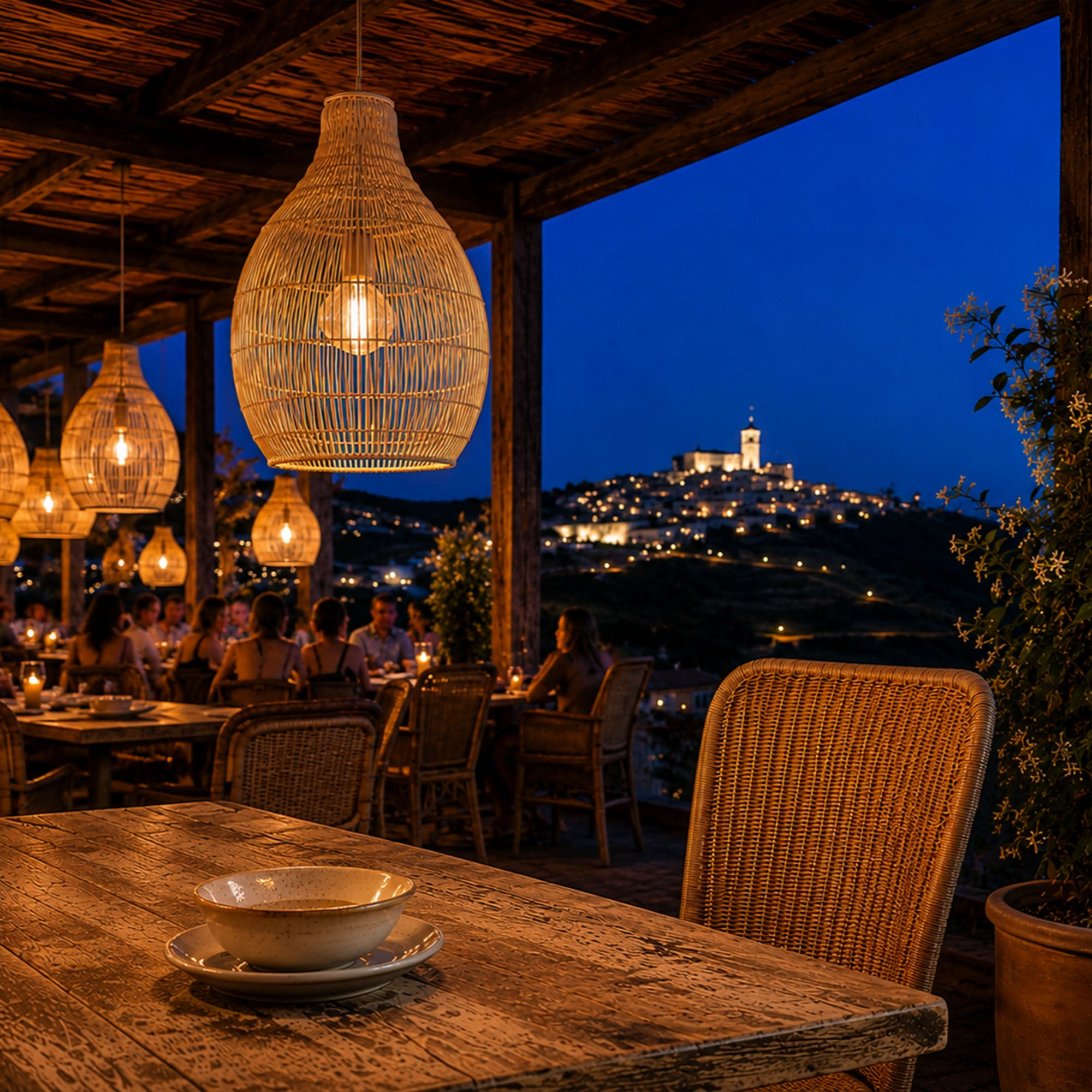 Ein Restaurant im Freien bei Nacht mit Blick auf eine beleuchtete Stadt auf einem Hügel.