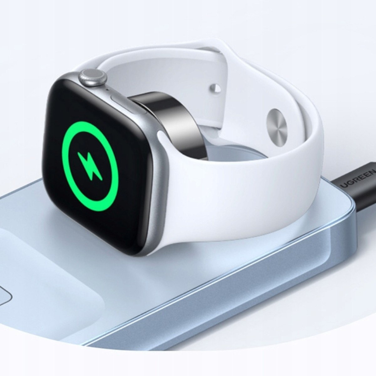 Biały smartwatch z zieloną ikoną błyskawicy ładuje się na powerbanku.