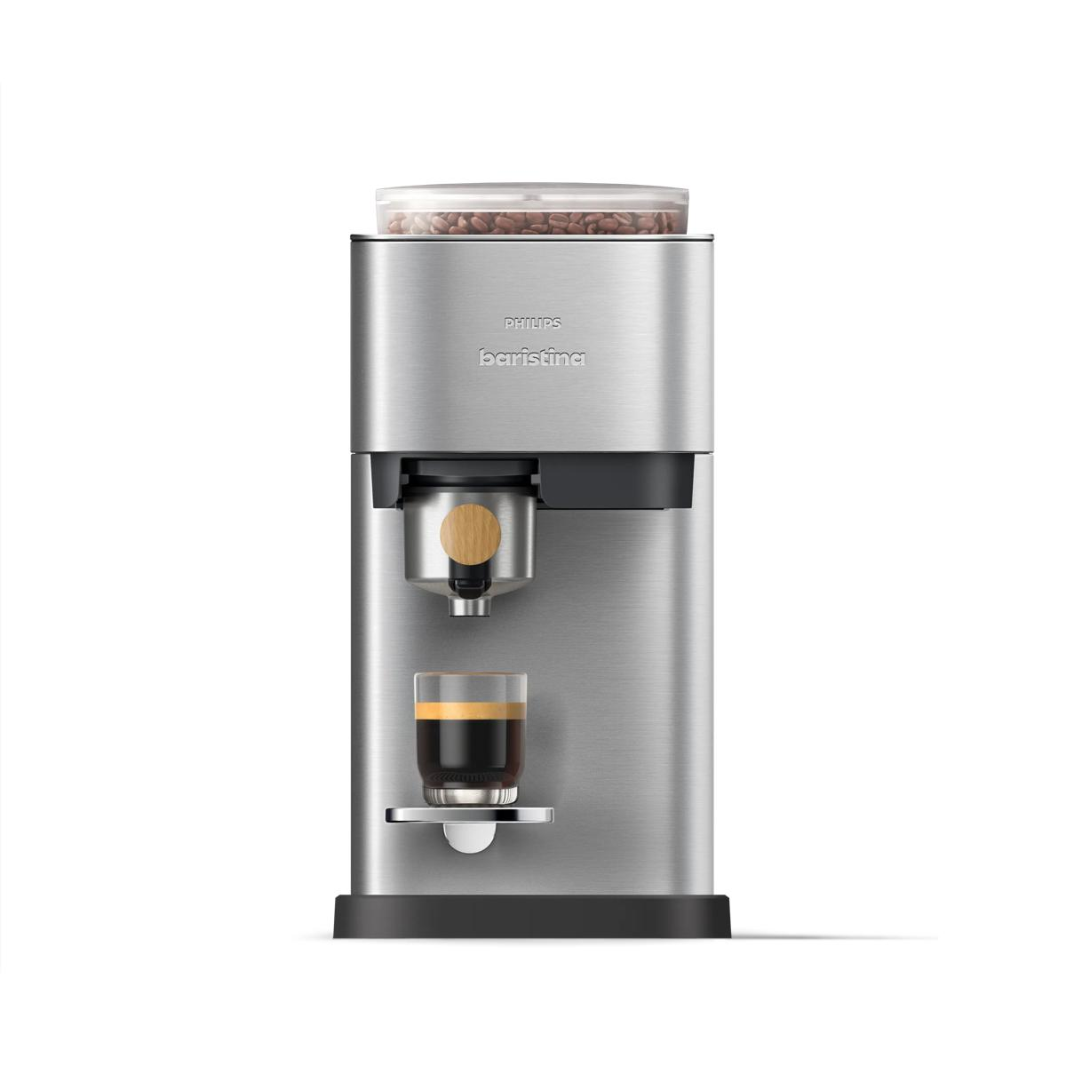 Macchina da caffè argento con chicchi sopra, espresso in bicchiere, dettaglio legno.