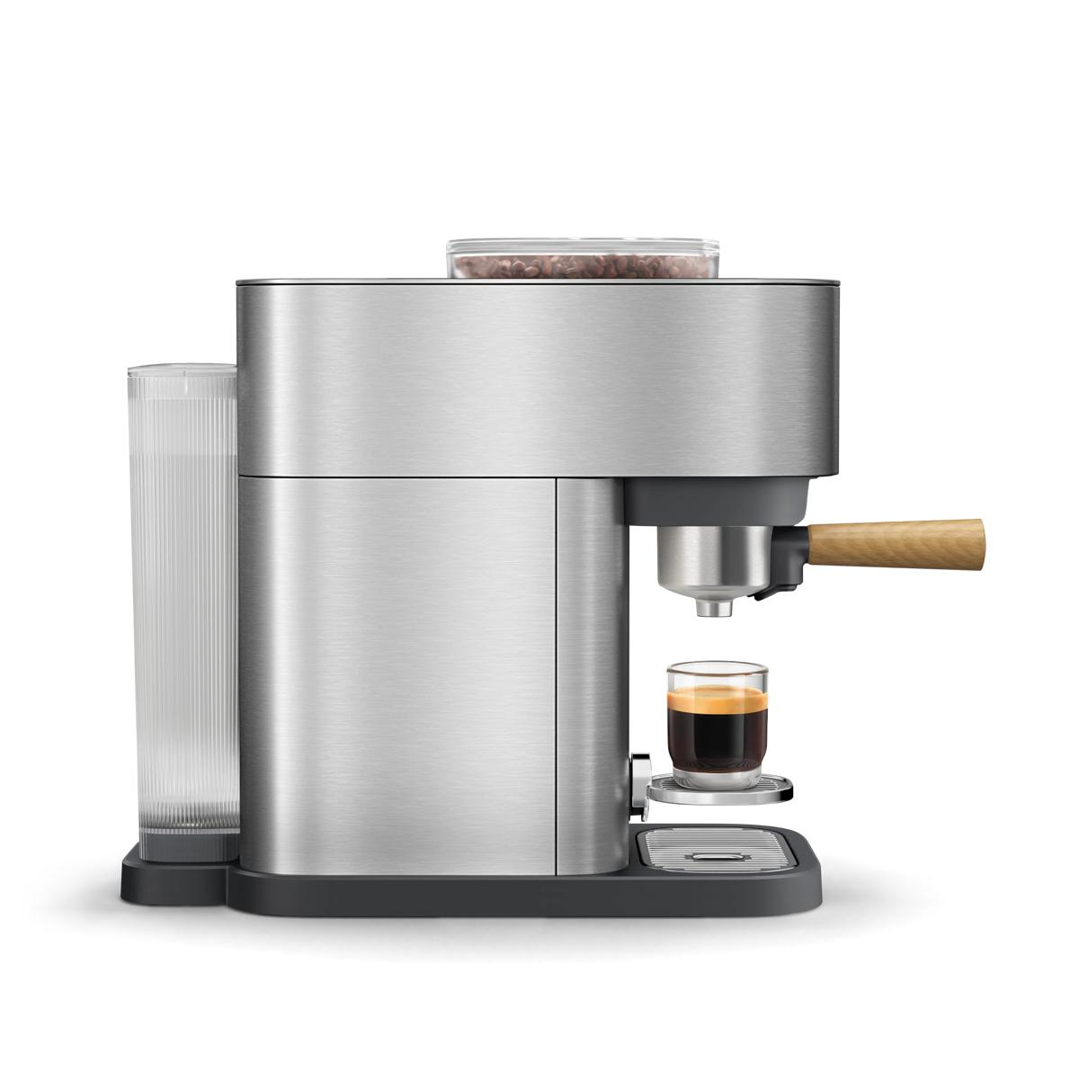 Macchina per espresso argentata con manico in legno, che eroga in una tazza di vetro.