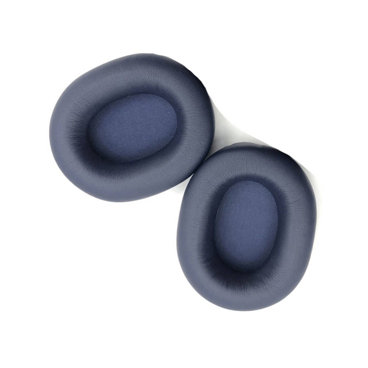 Due cuscinetti auricolari blu scuro giacciono uno accanto all'altro su sfondo bianco.