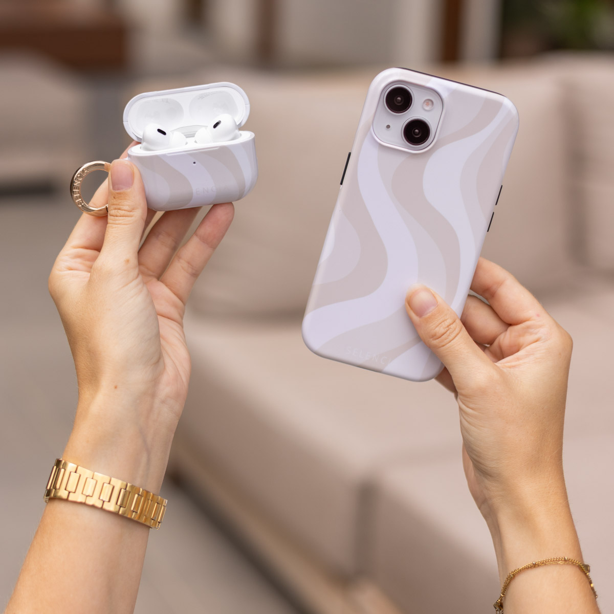 Manos sostienen un teléfono claro y funda blanca para audífonos con patrón ondulado.
