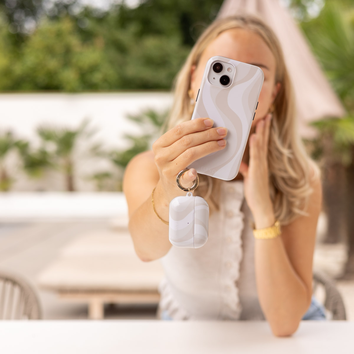 Mujer sosteniendo teléfono con patrón de ondas y llavero con funda a juego.