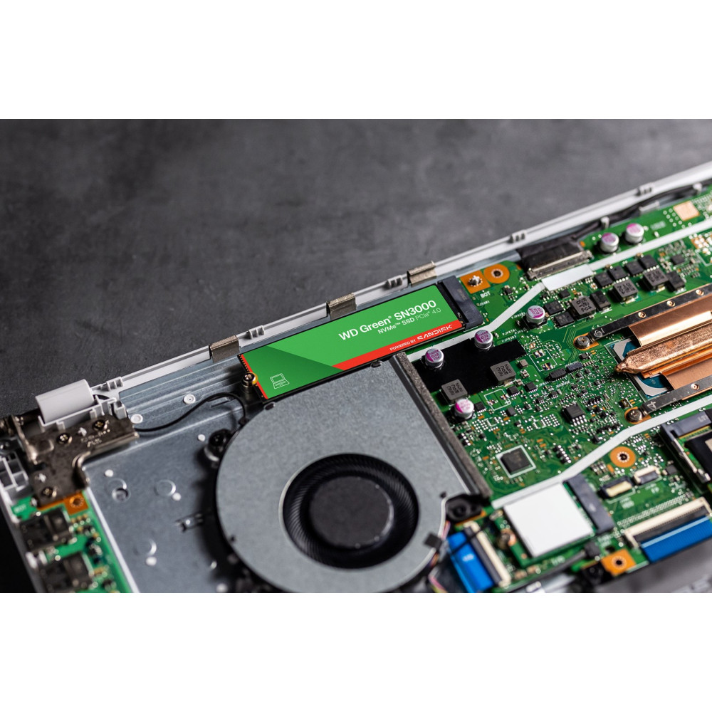 Zielona dysk SSD NVMe WD Green SN3000 na płycie głównej laptopa z wentylatorem.