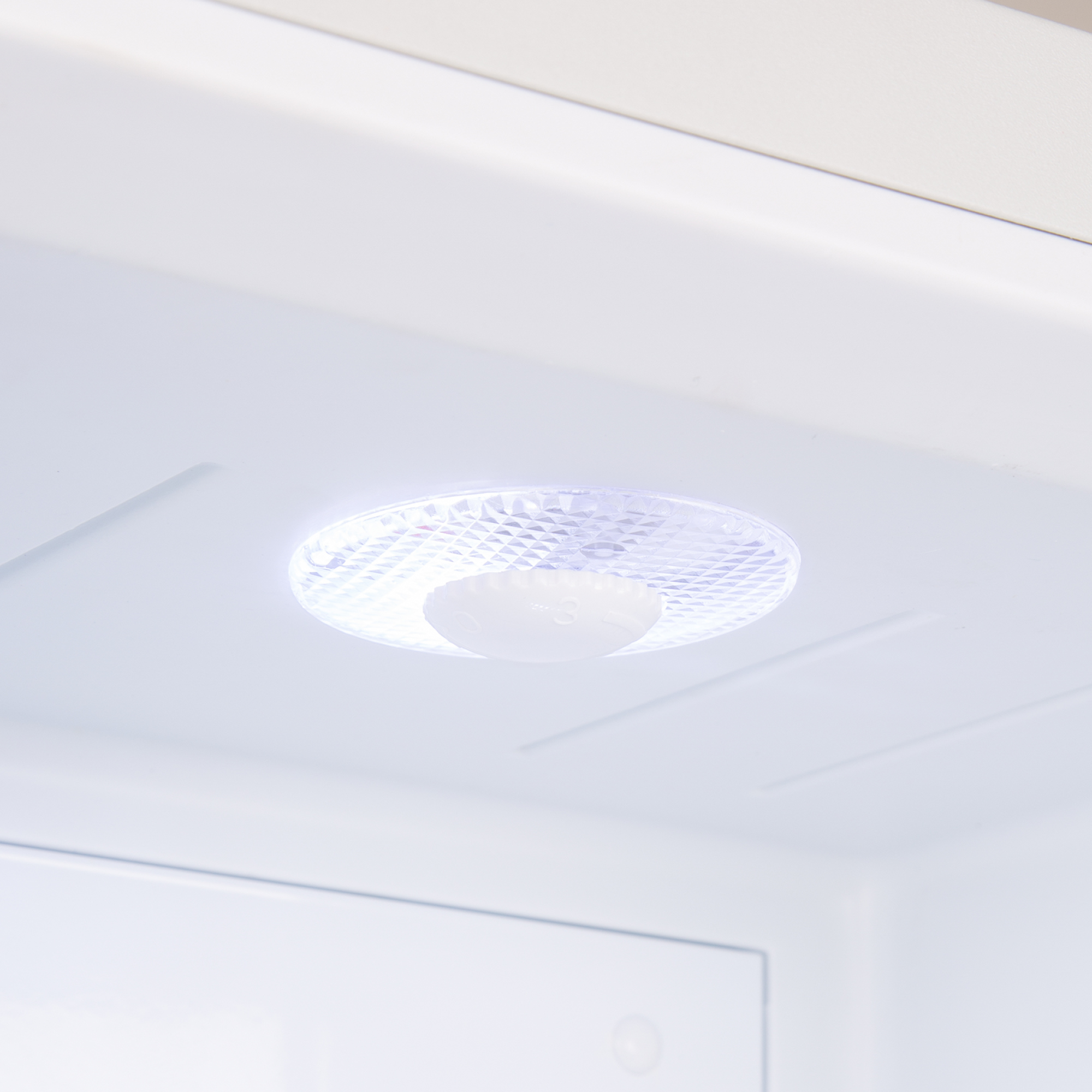 Ein beleuchteter Kühlschrankinnenraum mit einem runden LED-Licht.