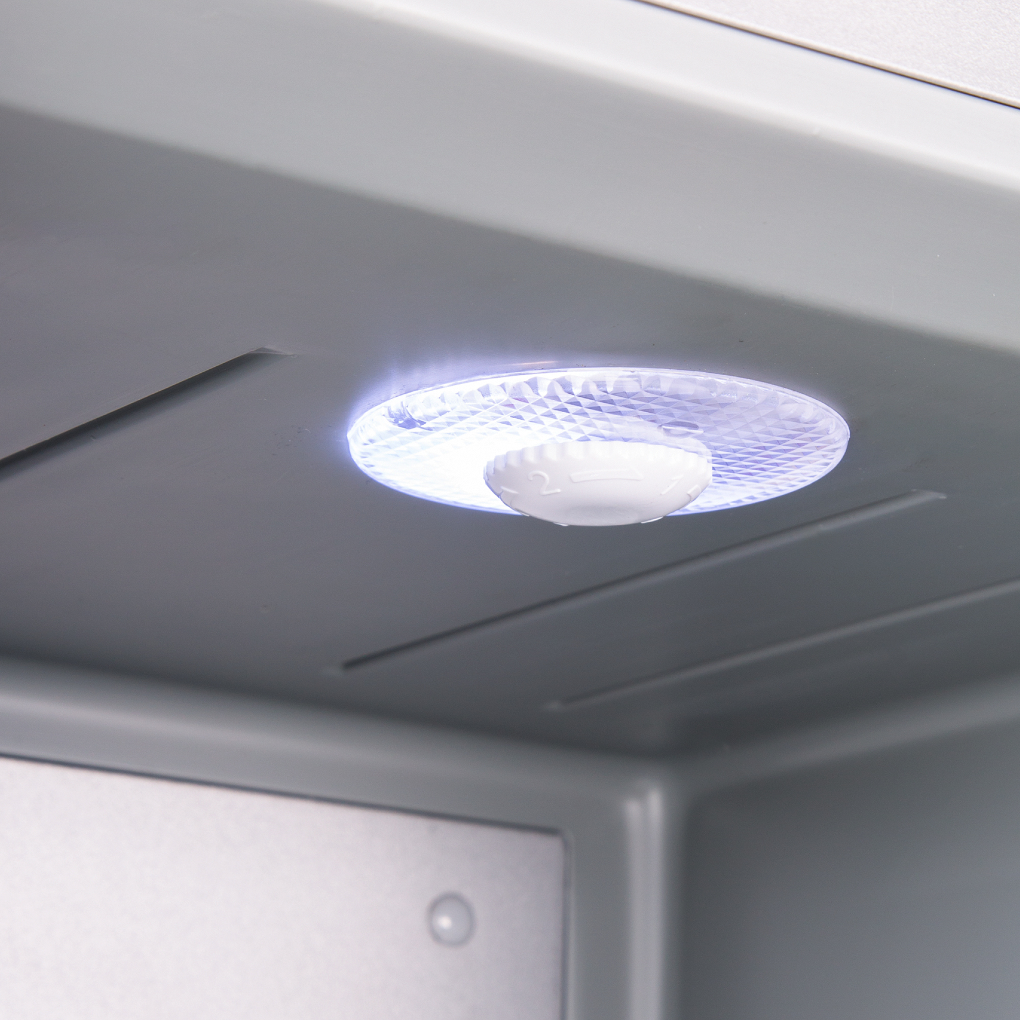 Un dial blanco con números 1 y 2 en una tapa texturizada e iluminada.