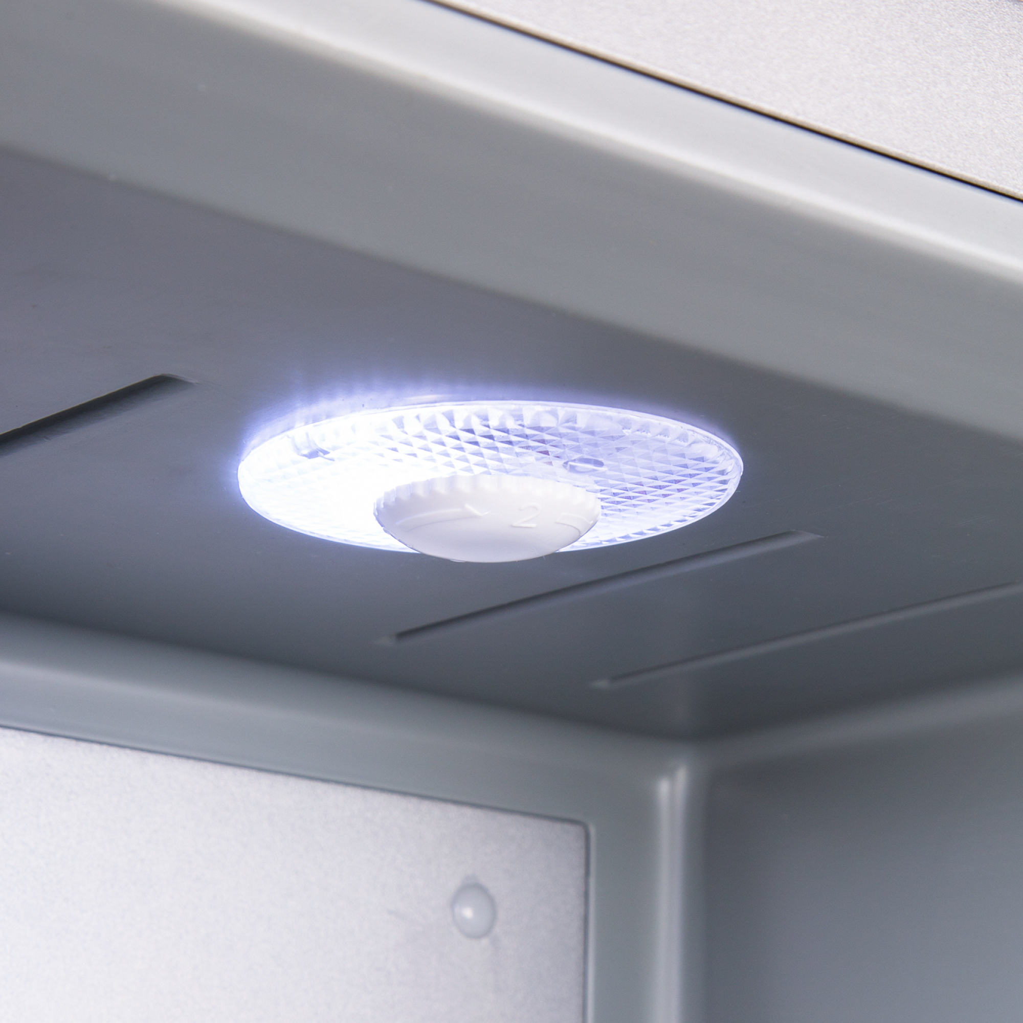 Eine helle LED-Leuchte mit strukturierter Abdeckung beleuchtet das Innere eines grauen Geräts.