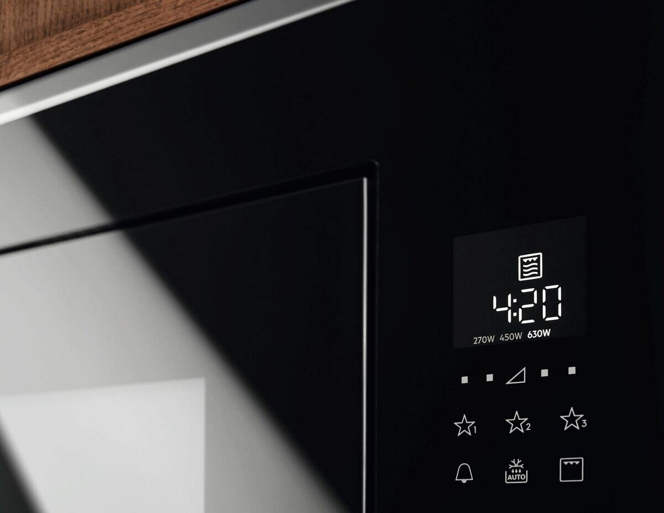 Primer plano de un microondas negro con pantalla digital que muestra 4:20.