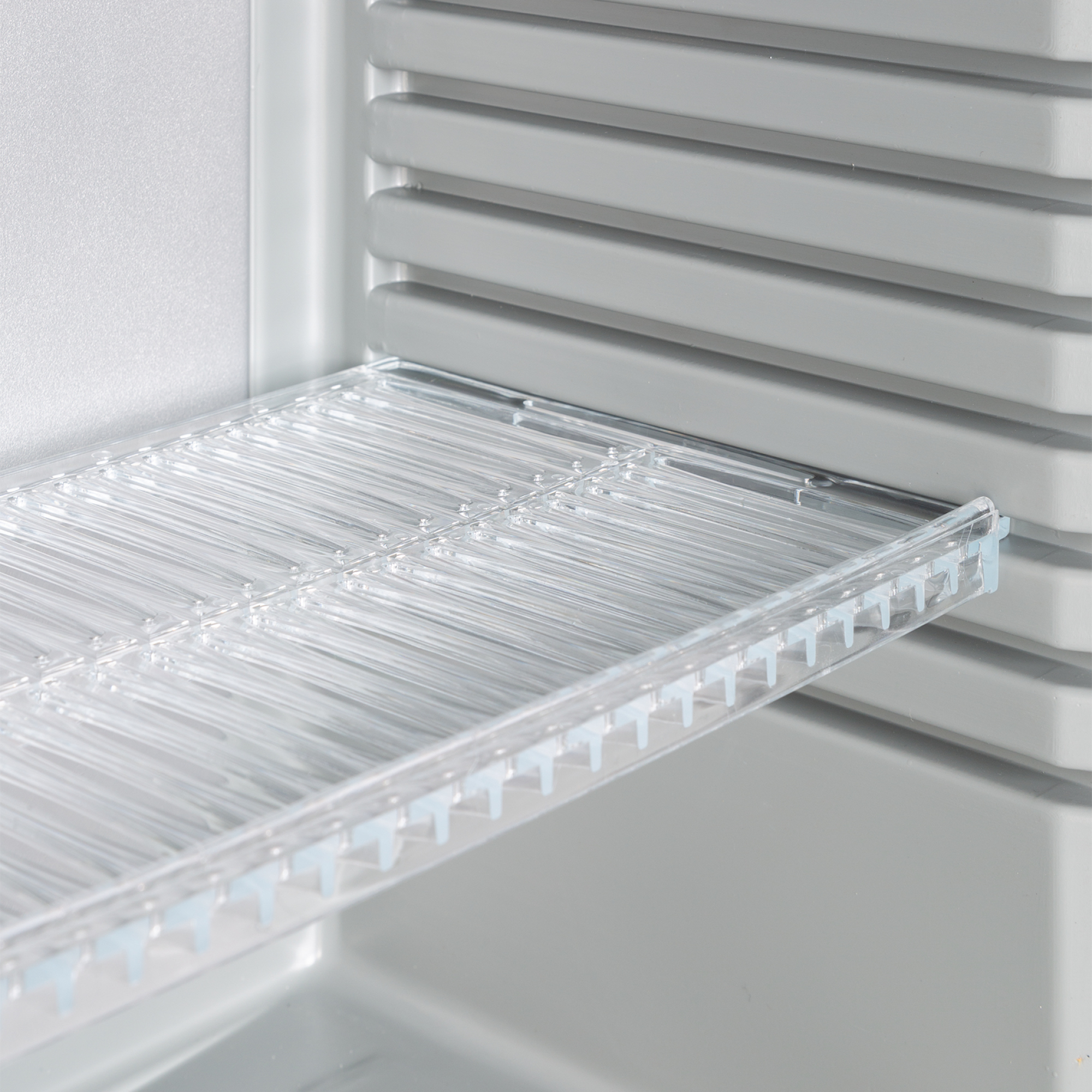 Un estante de refrigerador de plástico transparente con barras horizontales.