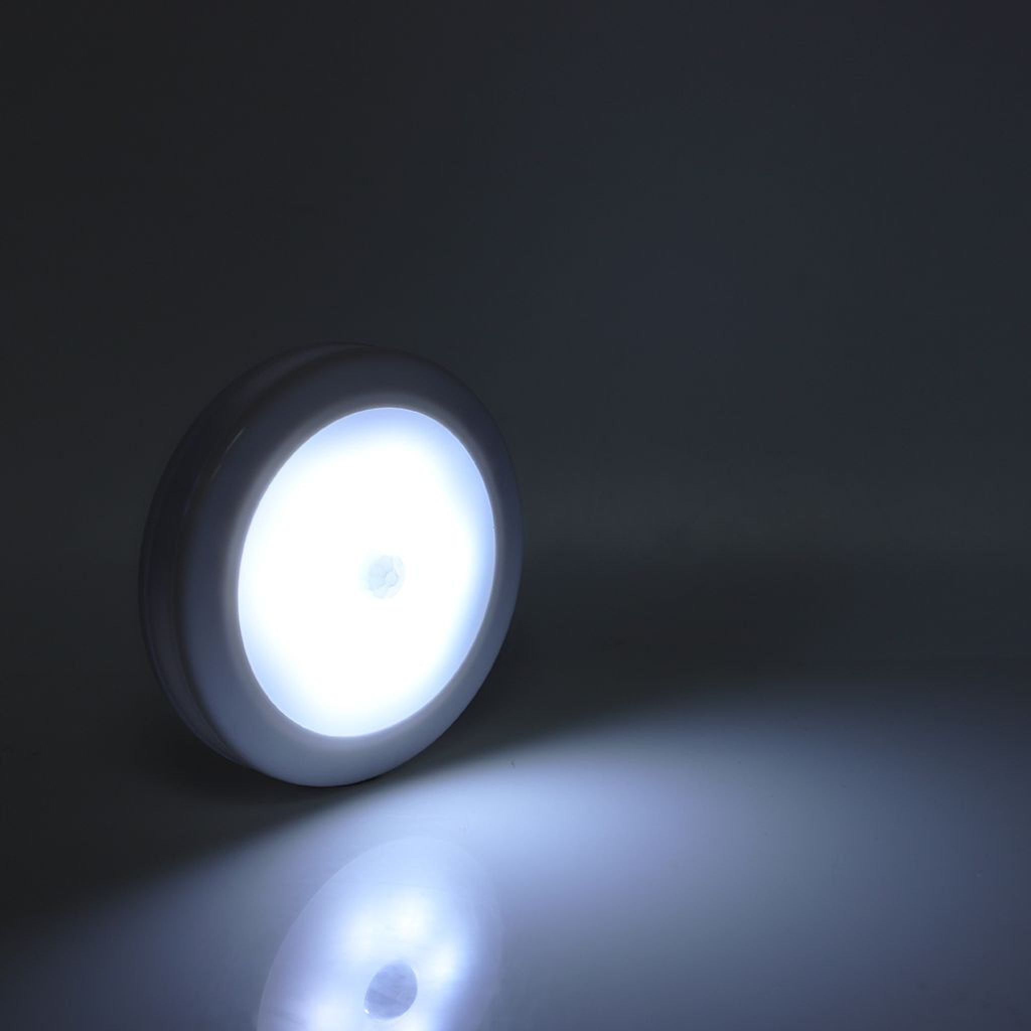 Ein weißes, rundes Nachtlicht leuchtet hell auf einem dunklen Hintergrund.