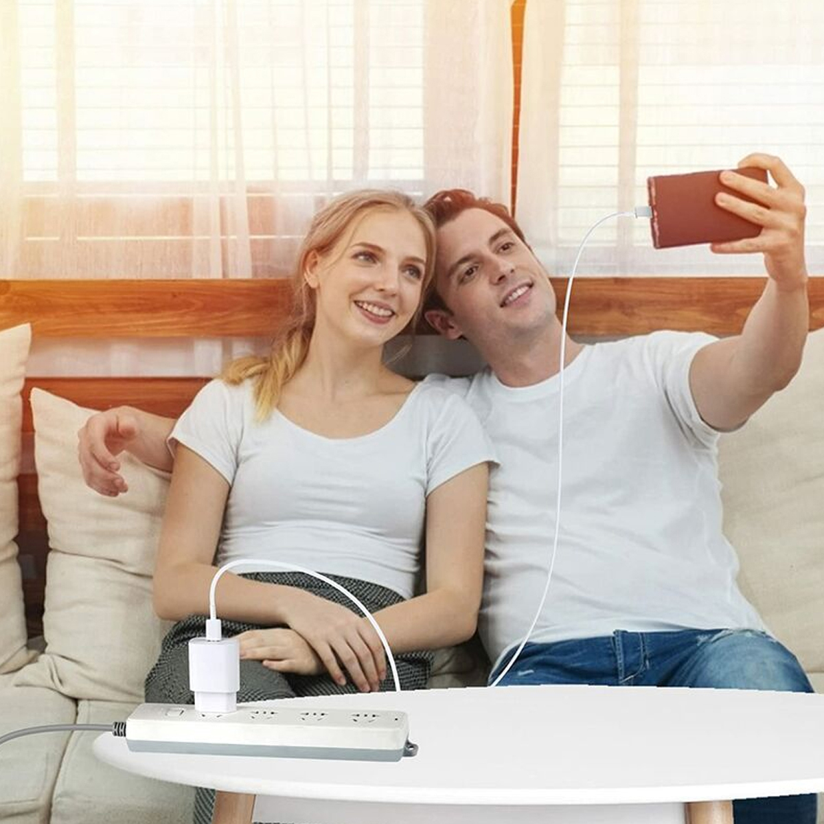 Ein Paar lächelt, während sie ein Selfie machen, während ihre Handys aufgeladen werden.