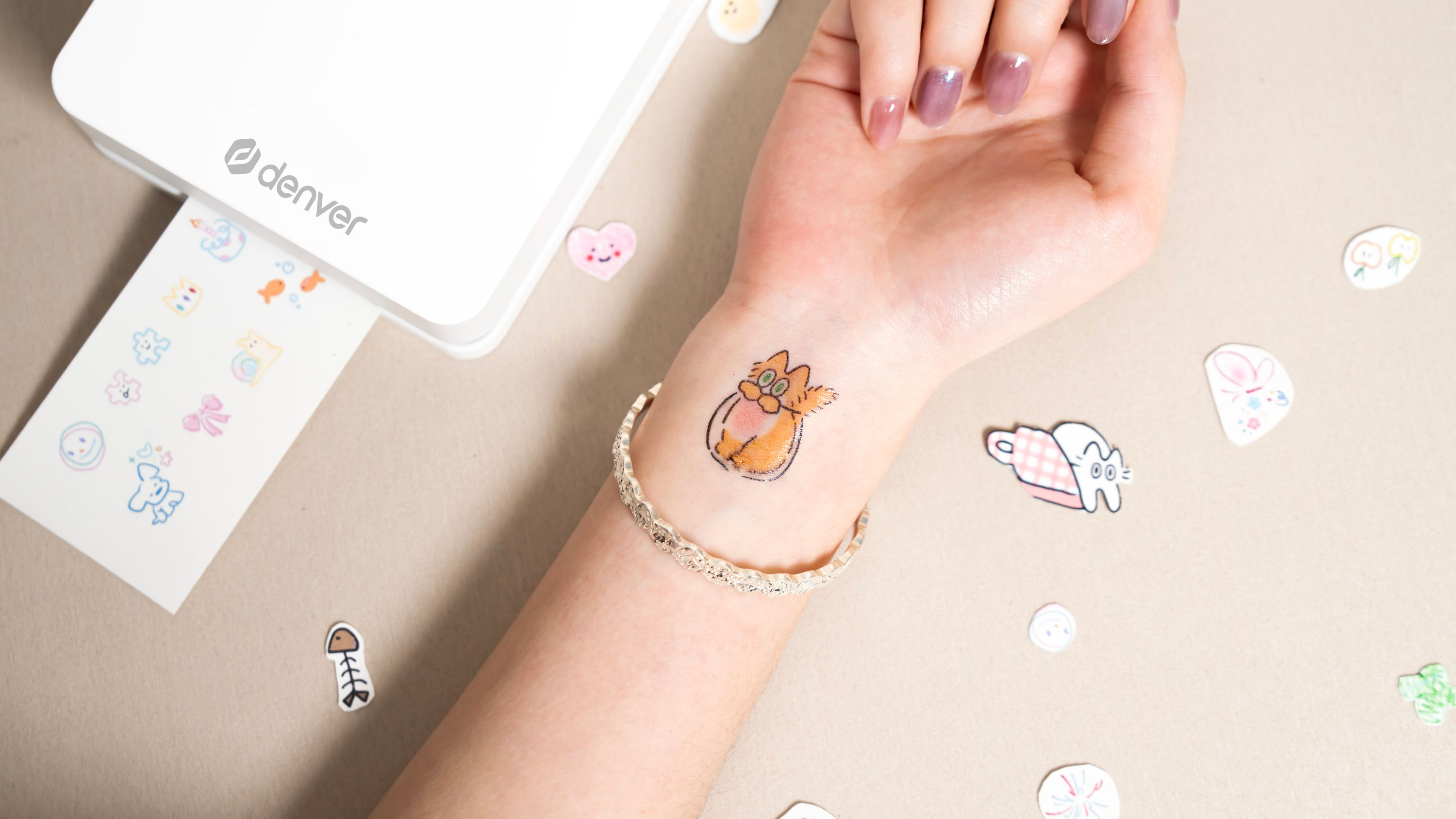 Eine Hand mit einem temporären Tattoo einer orangefarbenen Katze, umgeben von Stickern.